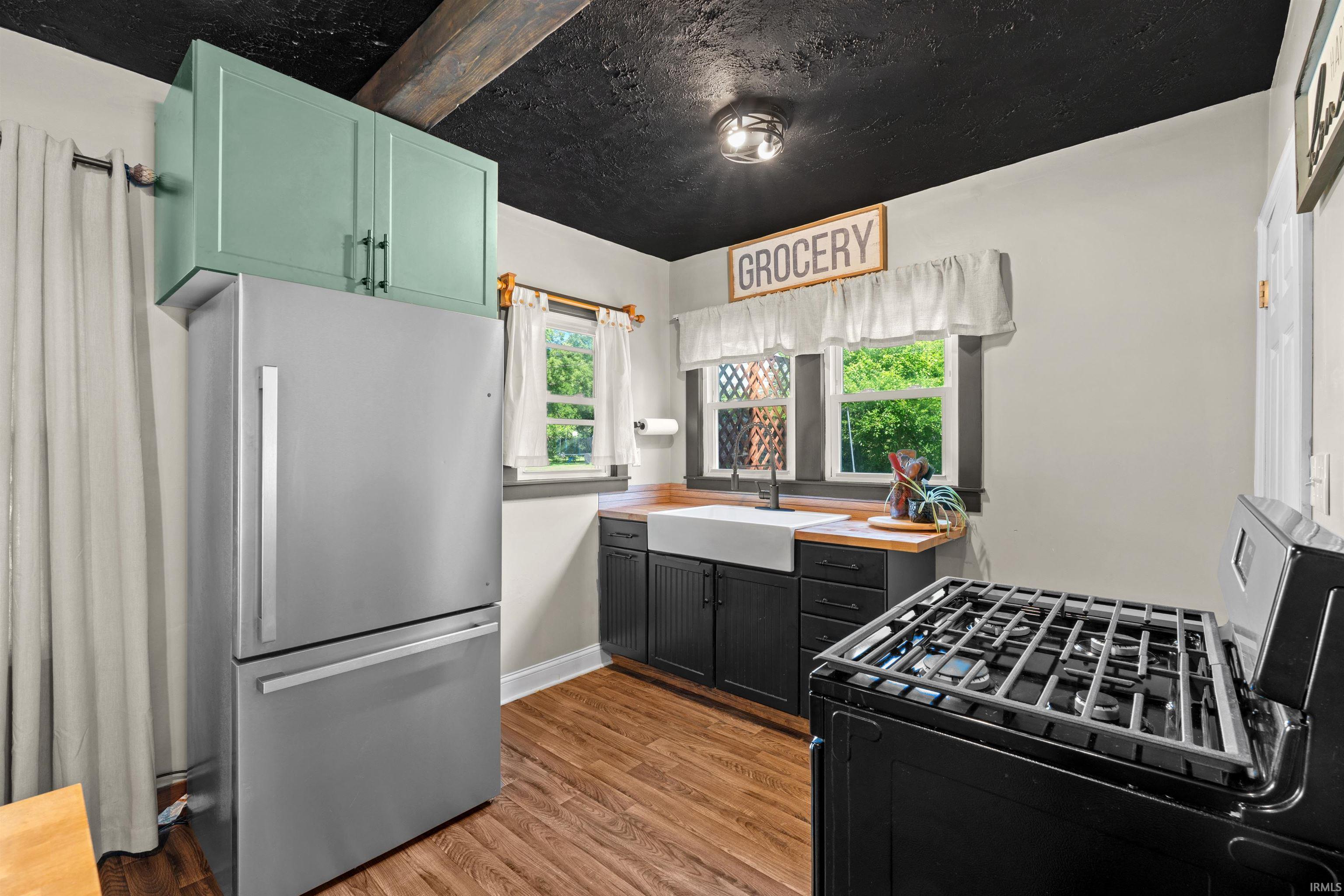 Kitchen featuring wood-finish flooring, dark cabinetry, and a farmhouse-style sink