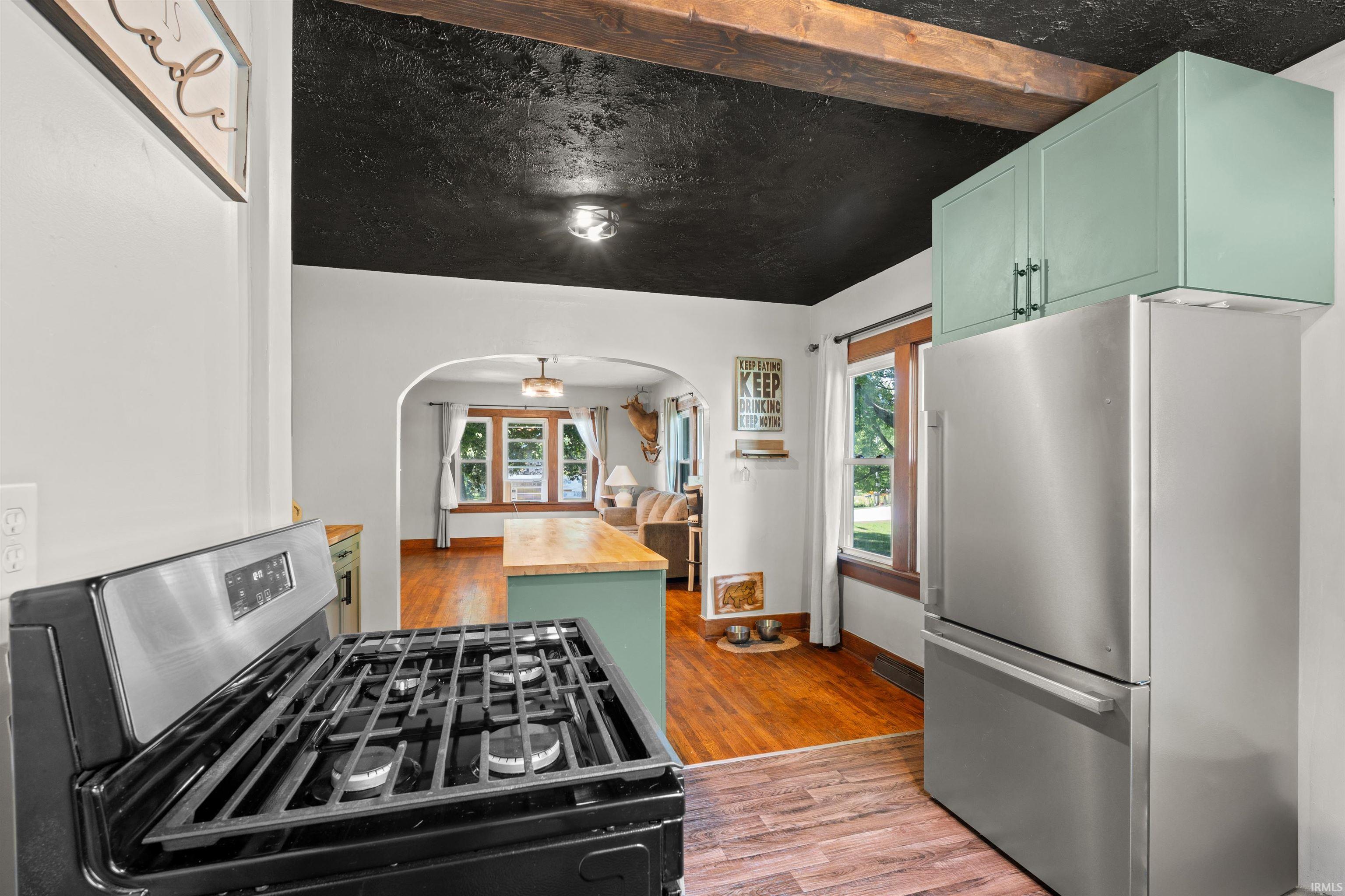 Kitchen featuring a stainless steel refrigerator, mint green upper cabinetry, and a black gas range
