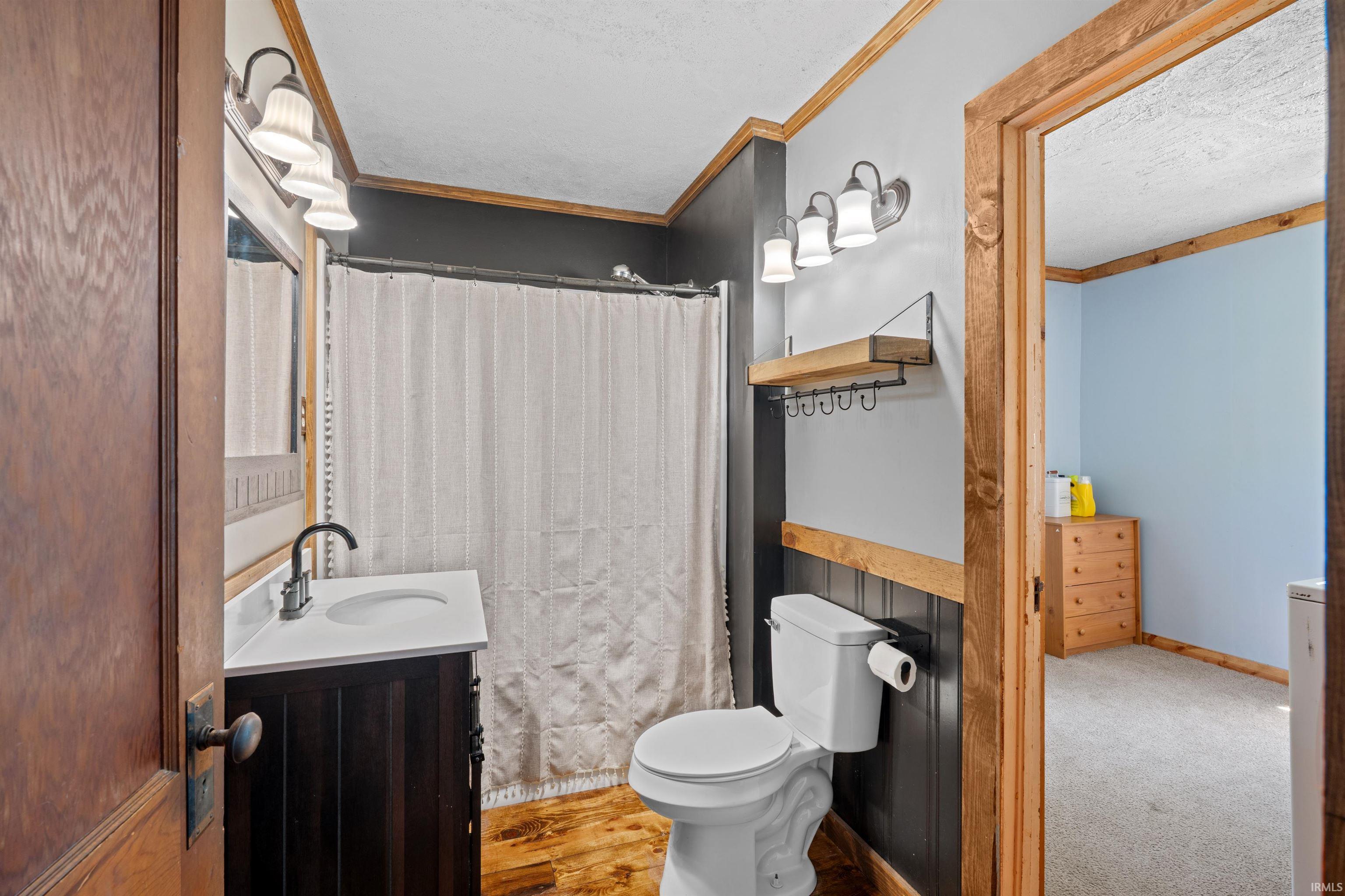Full bathroom featuring a dark wood-finish vanity with a white countertop and matte black faucet, a toilet, and a shower with a white curtain