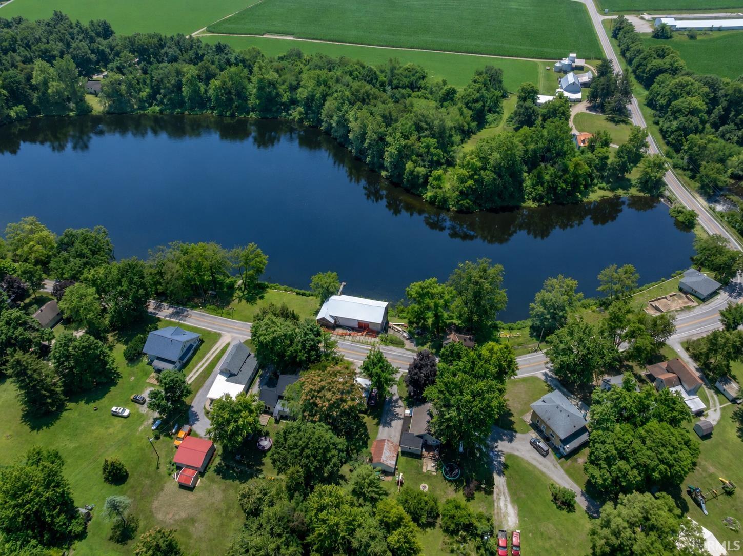 Aerial perspective of a body of water surrounded by green trees and agricultural fields