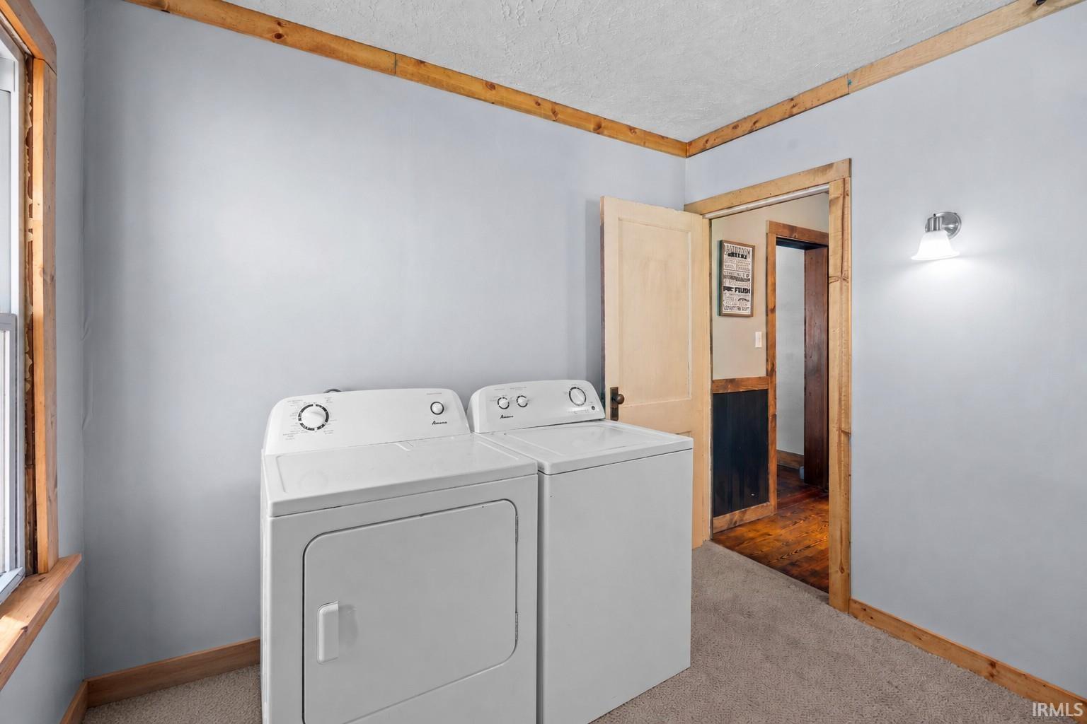 Dedicated laundry area featuring a washer and dryer set, carpeted flooring, and light blue walls