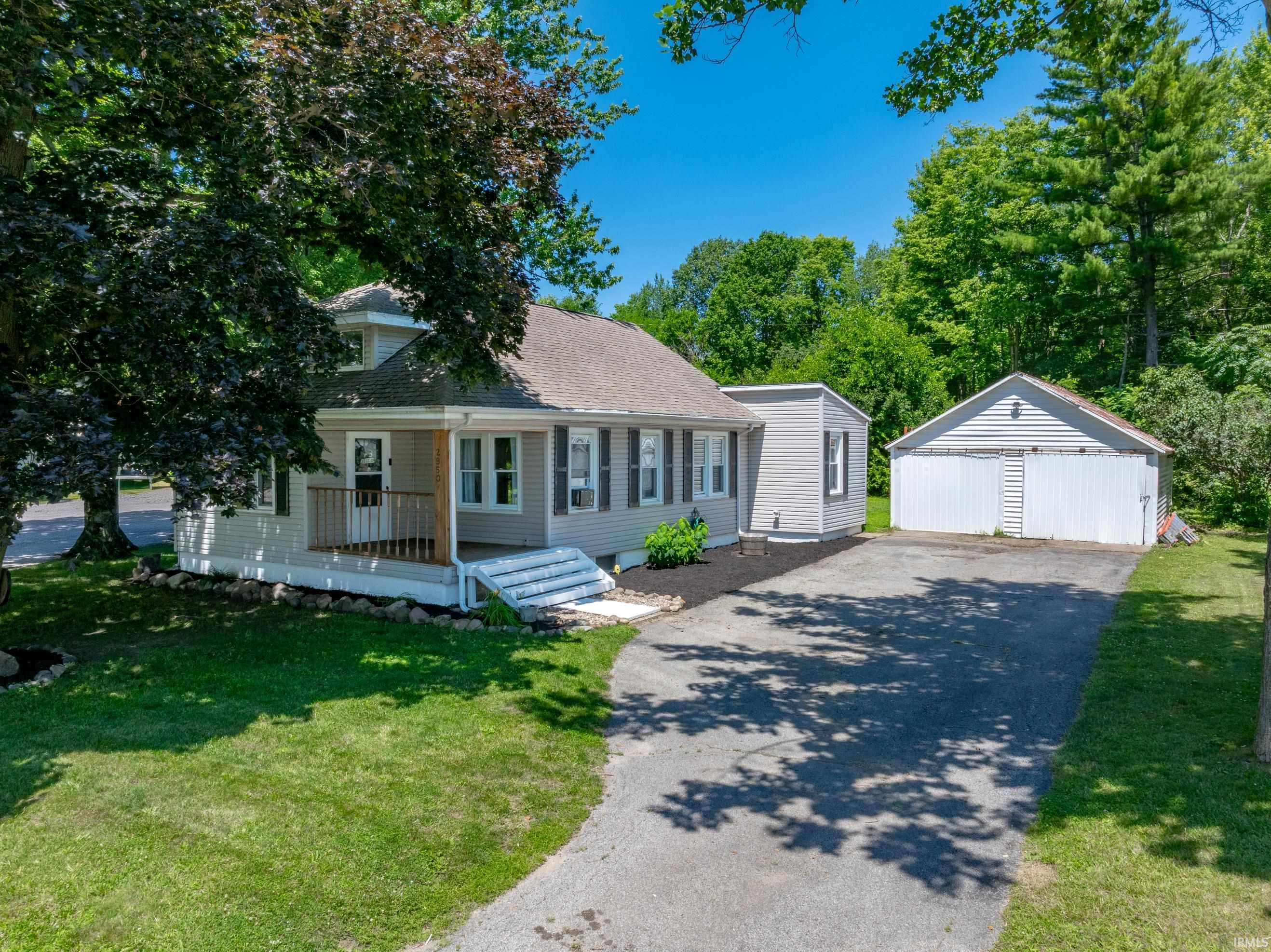 Charming residence featuring light gray siding, a covered front porch, and a dormer window