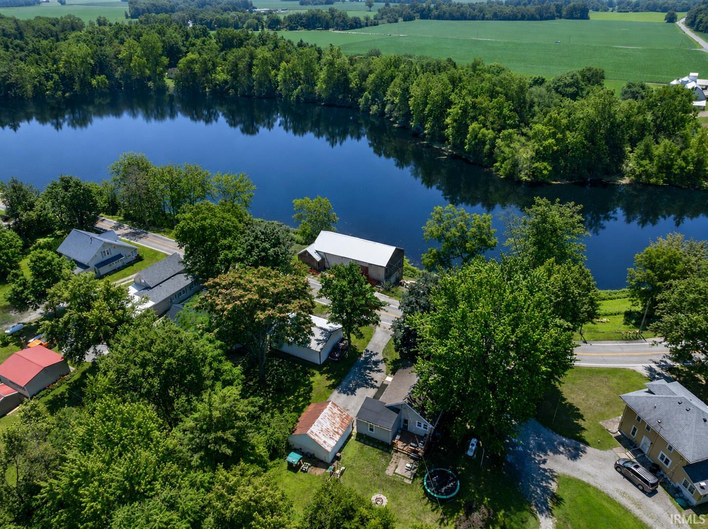 Waterfront properties featuring diverse architectural styles, mature trees, and a paved road