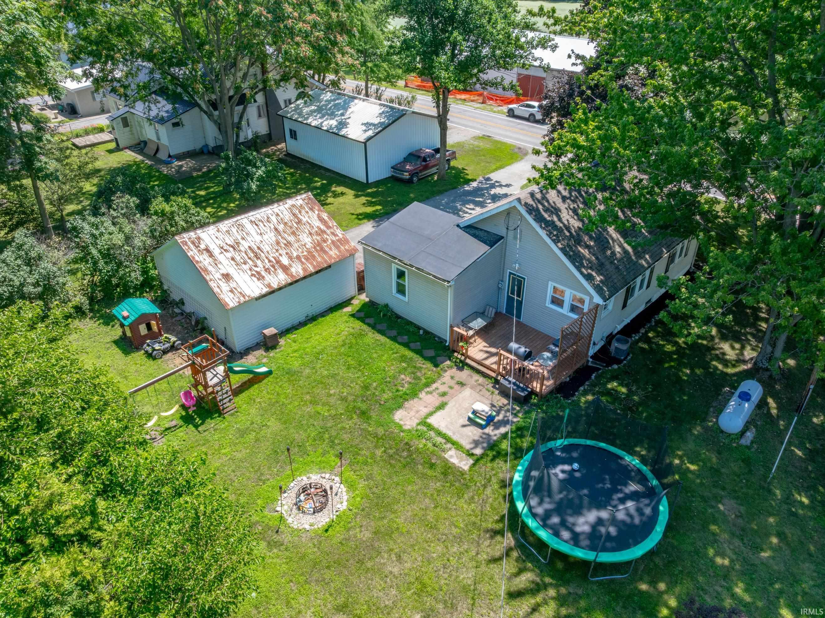 Aerial perspective showcasing a single-story dwelling with a rear deck, a detached garage, and an additional outbuilding