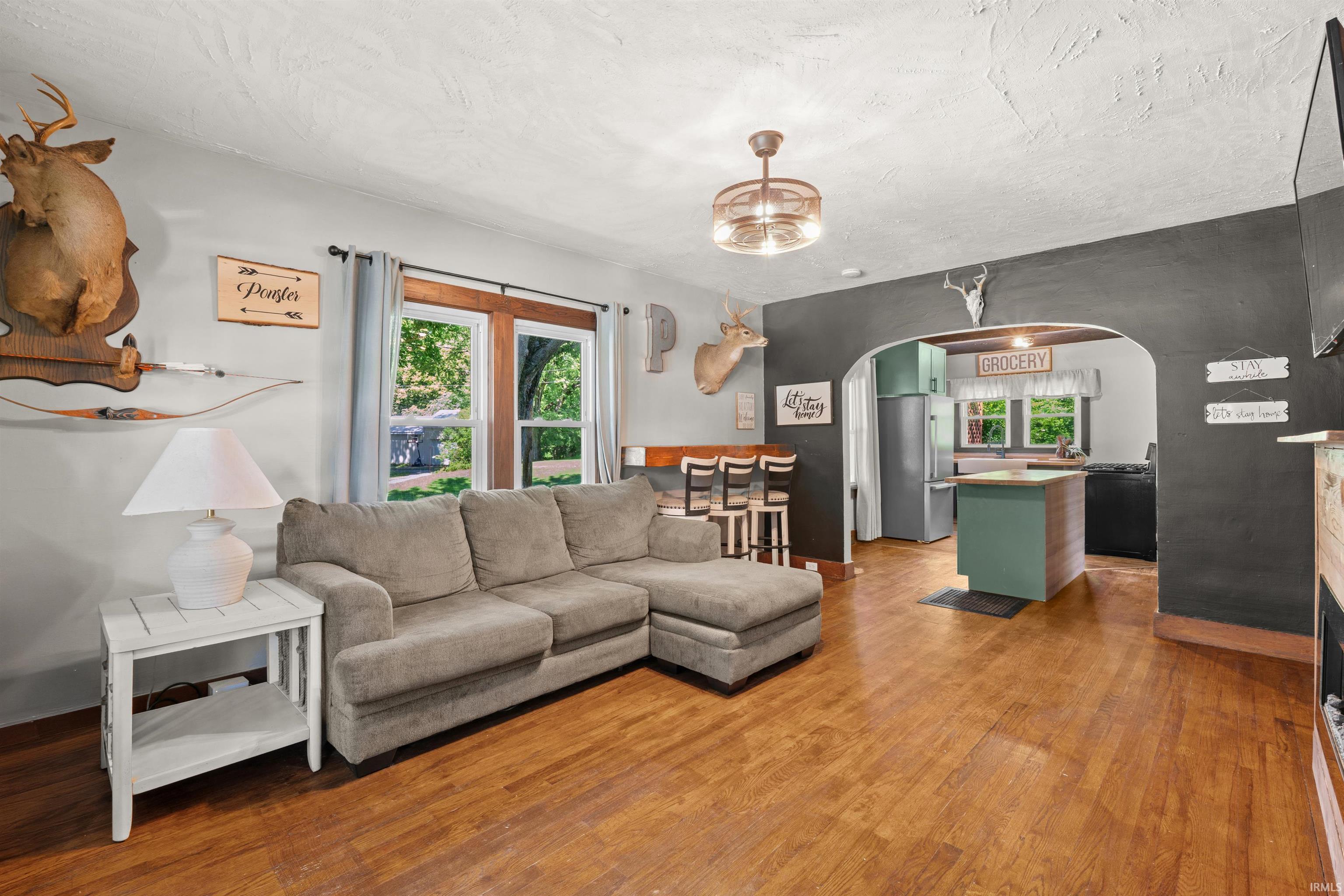 Open-concept living area featuring wood-finish flooring, a recessed arched doorway, and a ceiling fan with integrated lighting