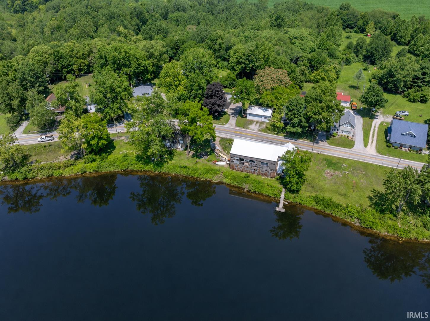 Waterfront property featuring a private dock, expansive green space, and a white roof structure