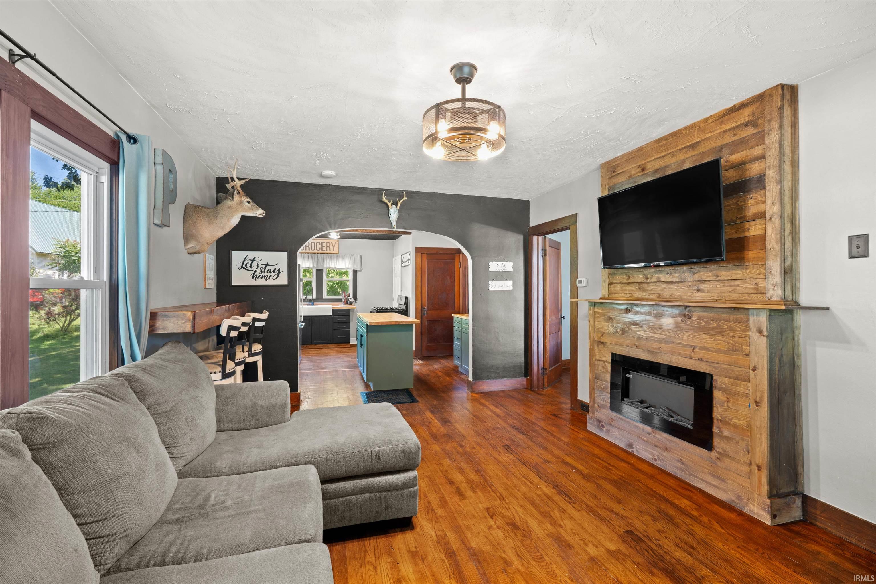 Living area featuring wood-finish flooring, a built-in fireplace with a wood-plank surround, and a coordinating wood-plank mantle