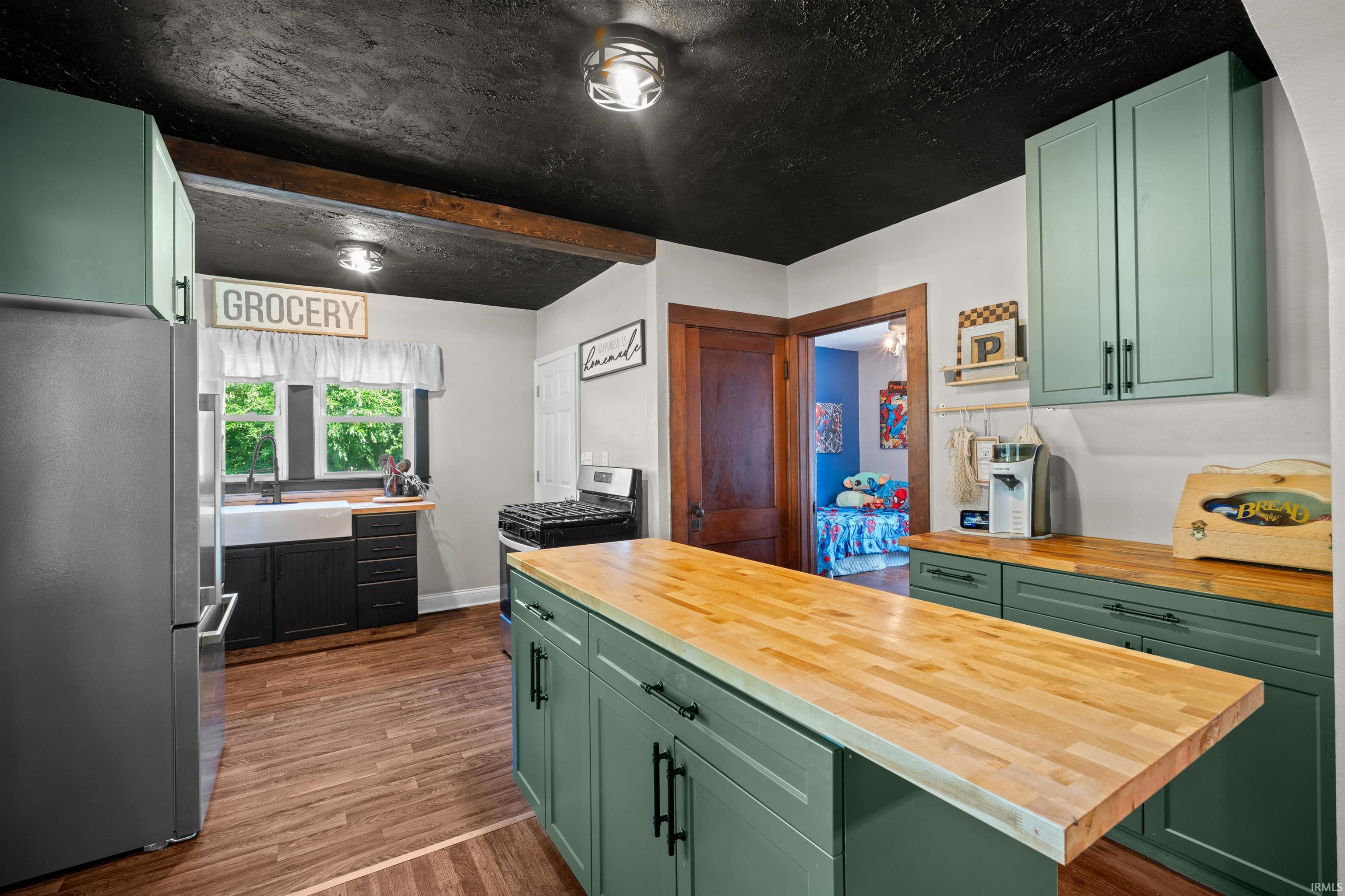Kitchen featuring a central island with a wood-finish countertop, coordinating lower cabinetry, and a black textured ceiling