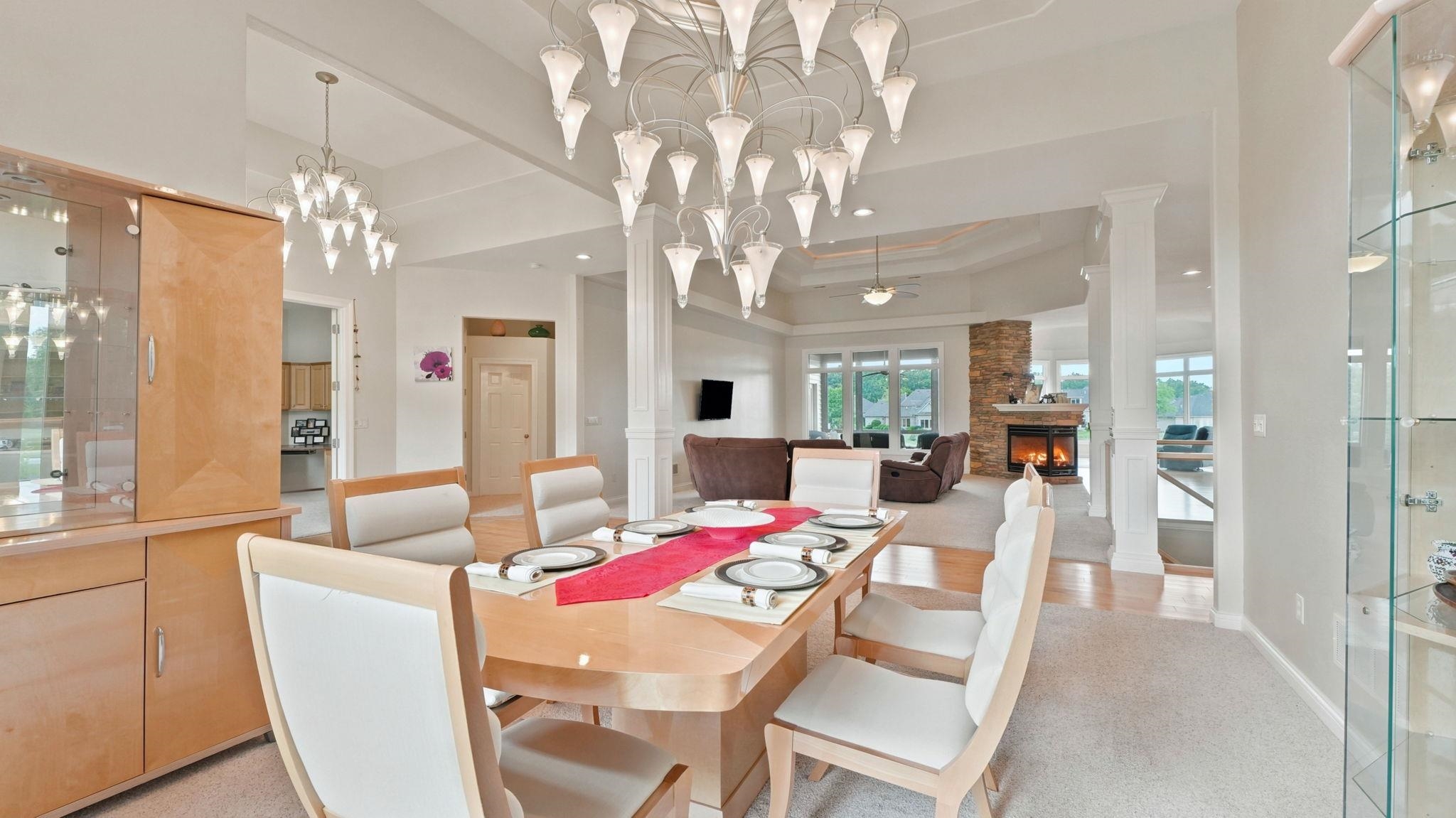 Dining area featuring a prominent multi-tiered chandelier, built-in display cabinetry, tray ceiling detail, and a carpeted floor