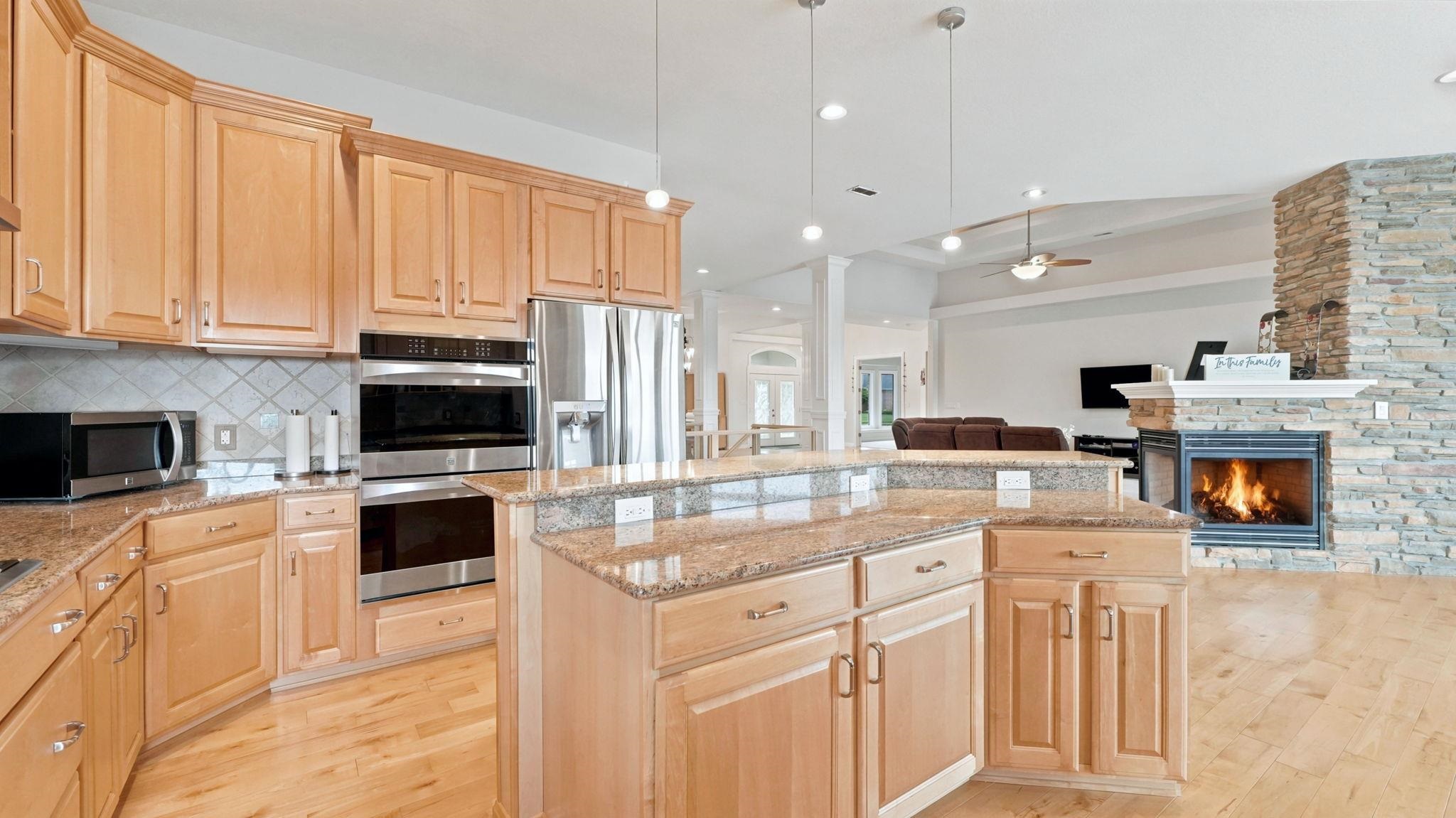 Open-concept kitchen featuring light-finish cabinetry, granite countertops, and stainless steel appliances