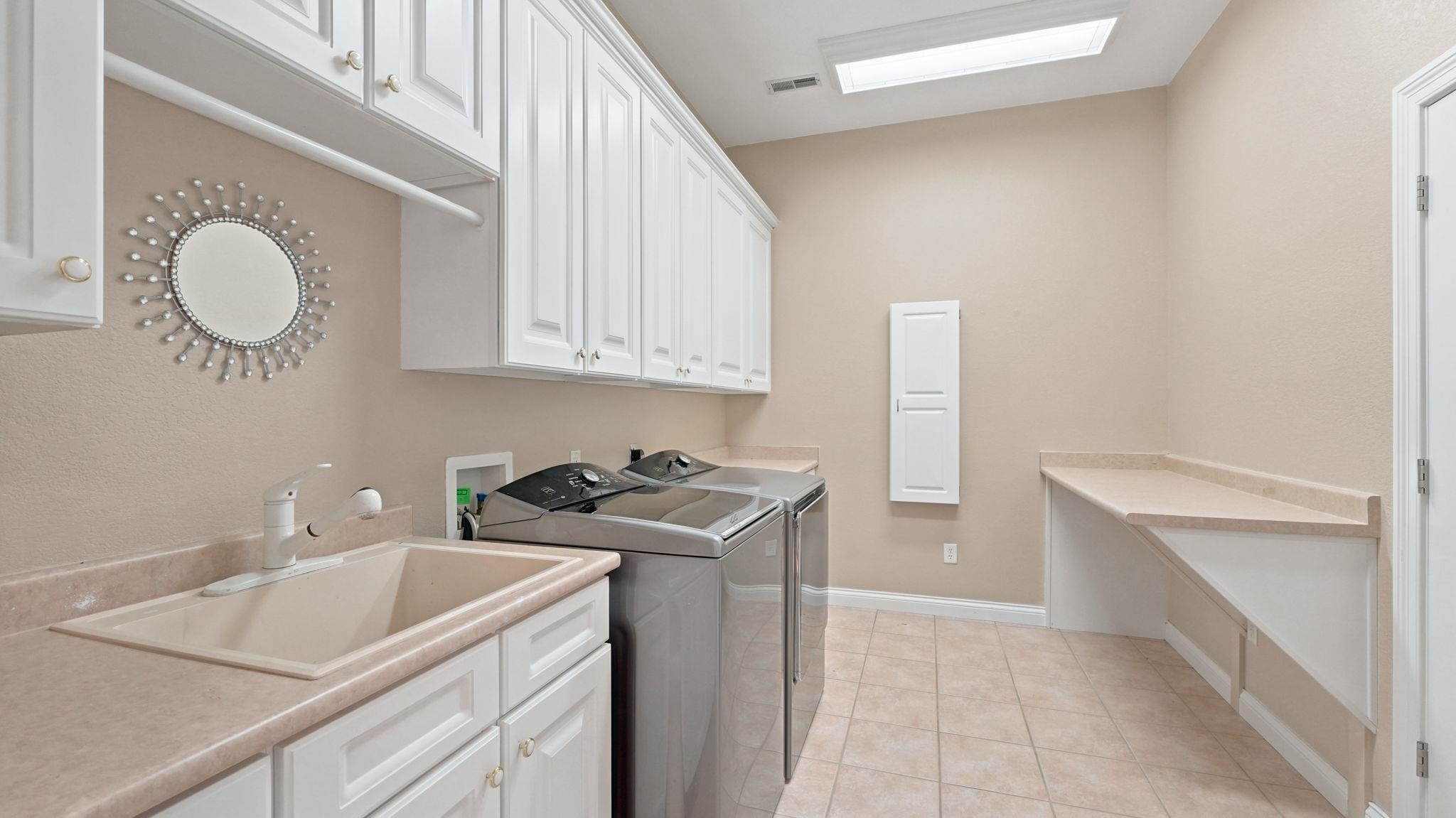 Laundry room featuring extensive white cabinetry, a built-in sink with countertop, and an additional built-in counter space