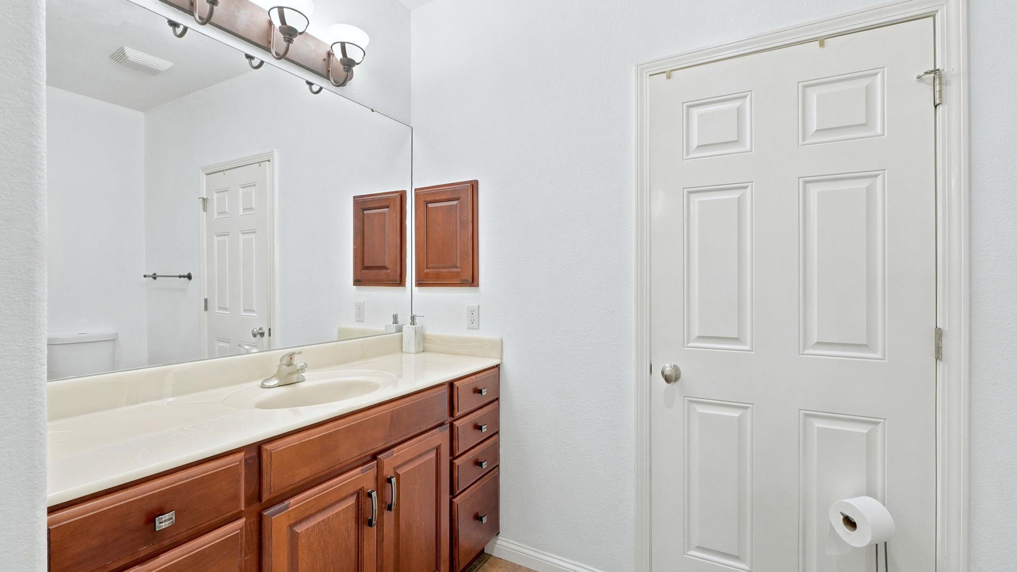 Bathroom vanity featuring a light-toned countertop, under-mount sink, and wood-finish cabinetry with multiple drawers and cabinet storage