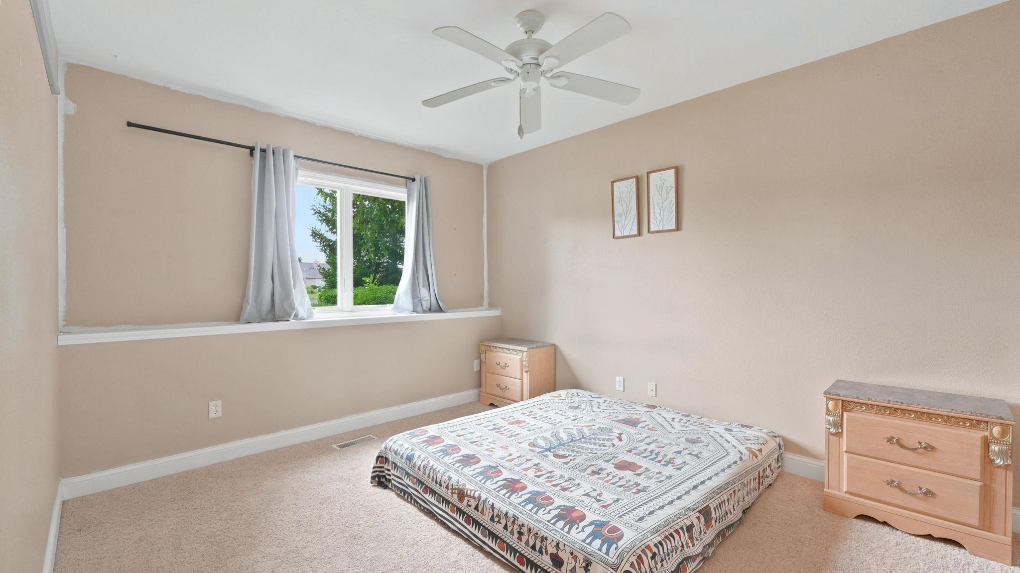 Carpeted room featuring a ceiling fan, a window with exterior views, and a white window ledge