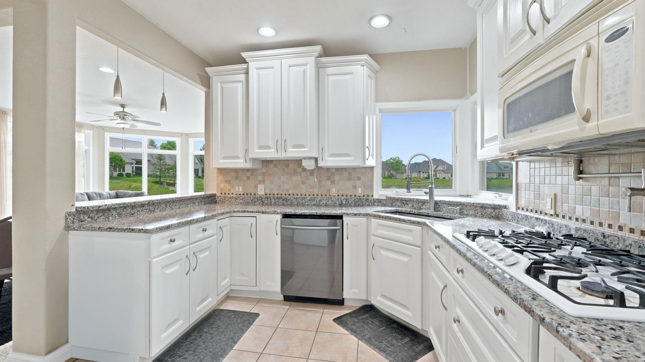 Kitchen featuring white cabinetry, granite countertops, stainless steel dishwasher, gas cooktop, and tile flooring