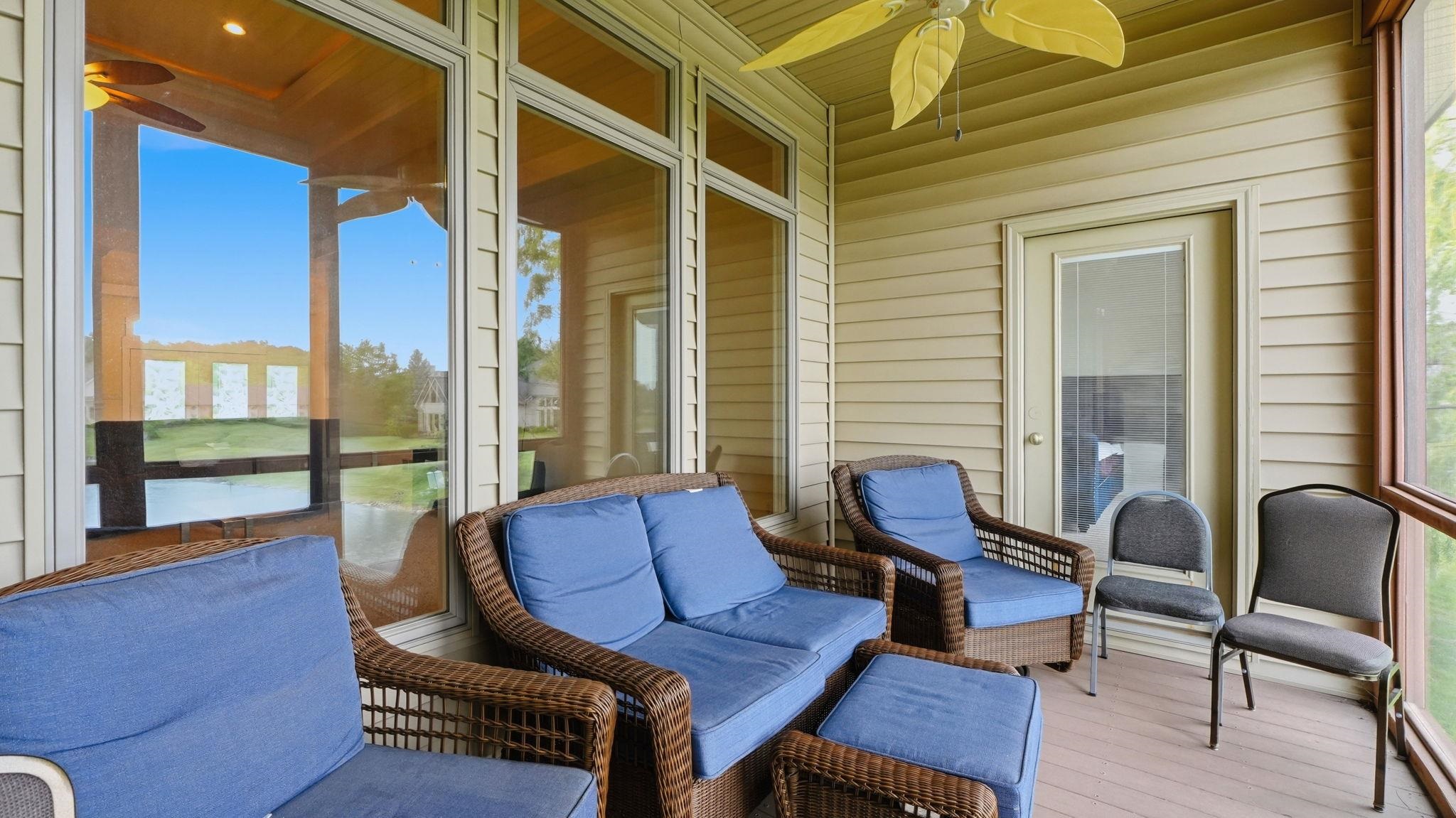 Screened porch featuring a ceiling fan, light tan siding, and a wooden deck floor