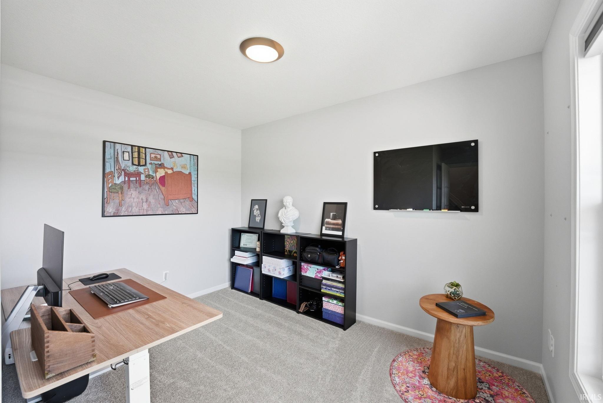 Neutral wall paint, light-colored carpeting, recessed ceiling light, and window providing natural illumination