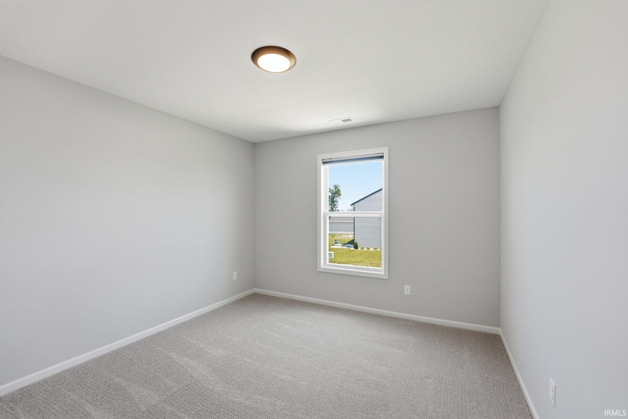 Bedroom with light gray walls, gray carpeting, and a single window with white trim