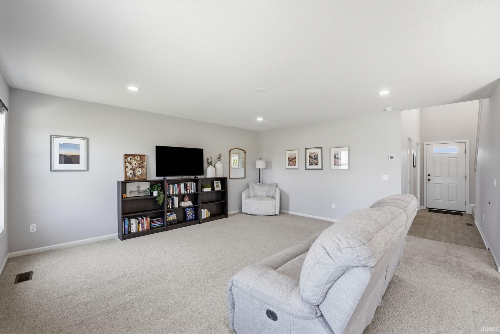 Spacious living area featuring light-colored carpeting and recessed lighting