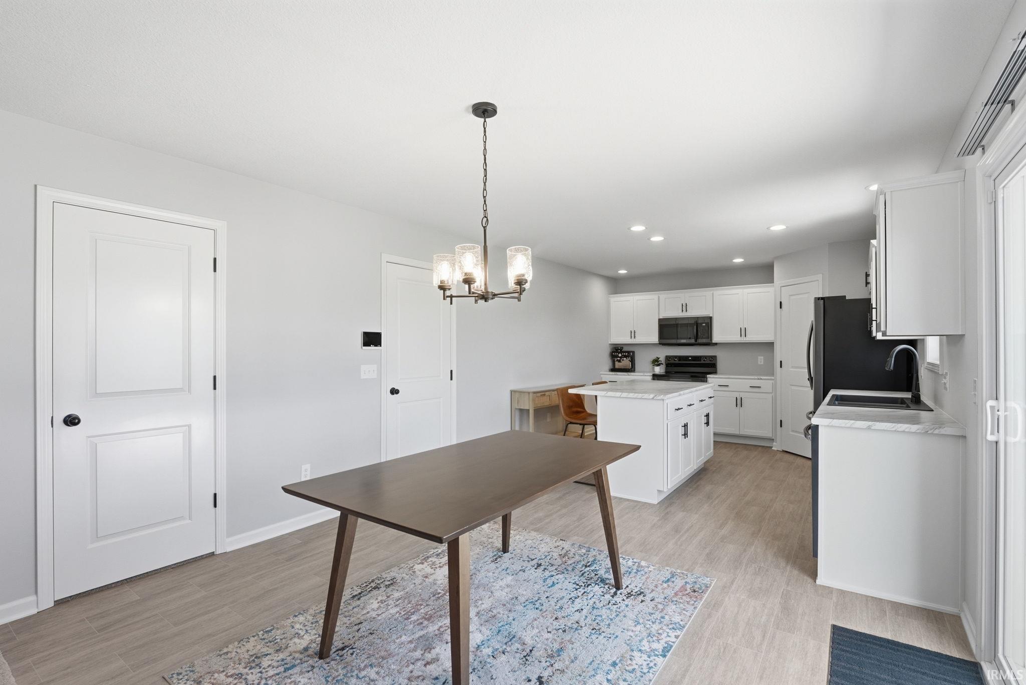Kitchen featuring white cabinetry, a central island with countertop seating, black appliances, and recessed lighting