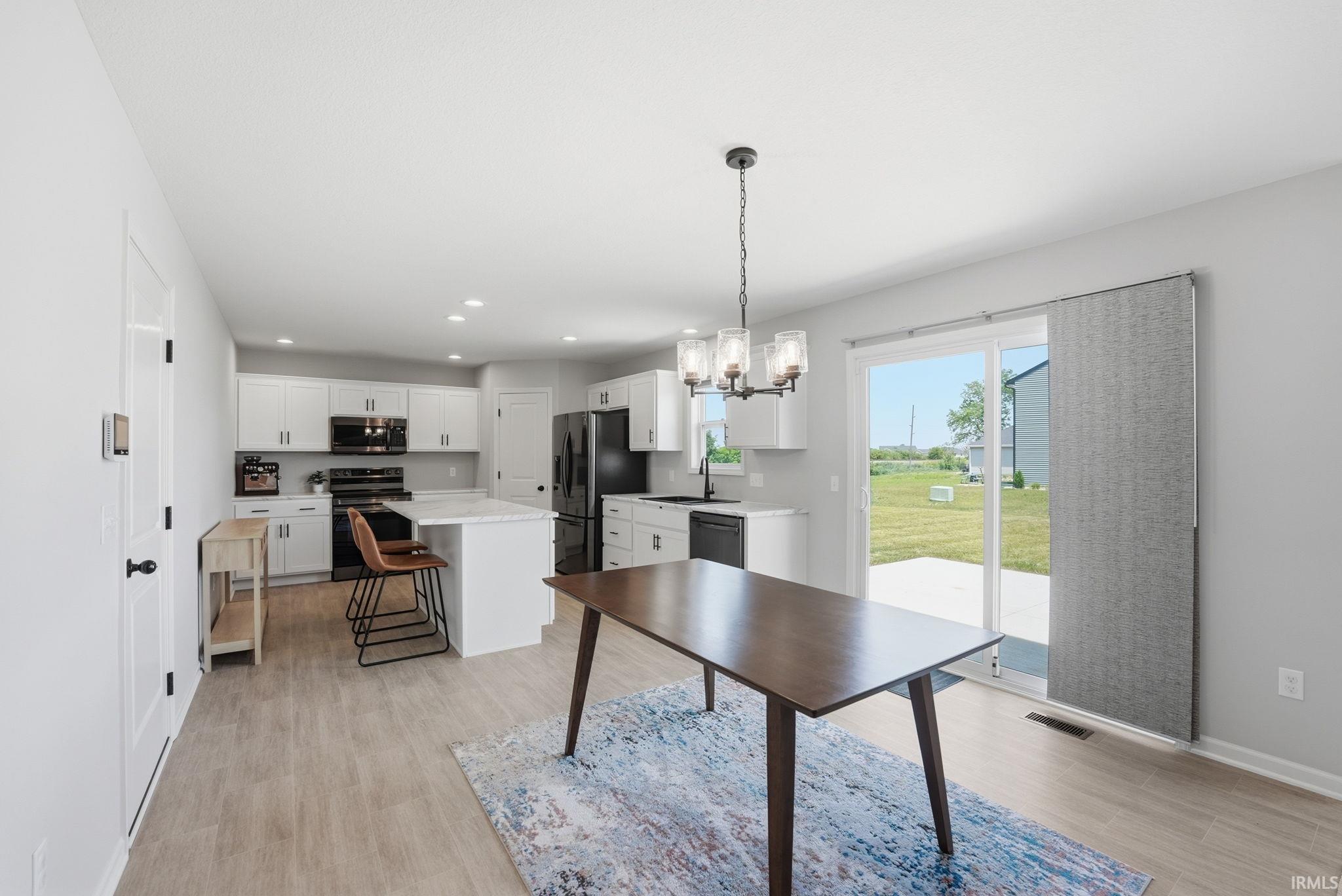 Open-concept kitchen and dining area featuring white cabinetry and black appliances