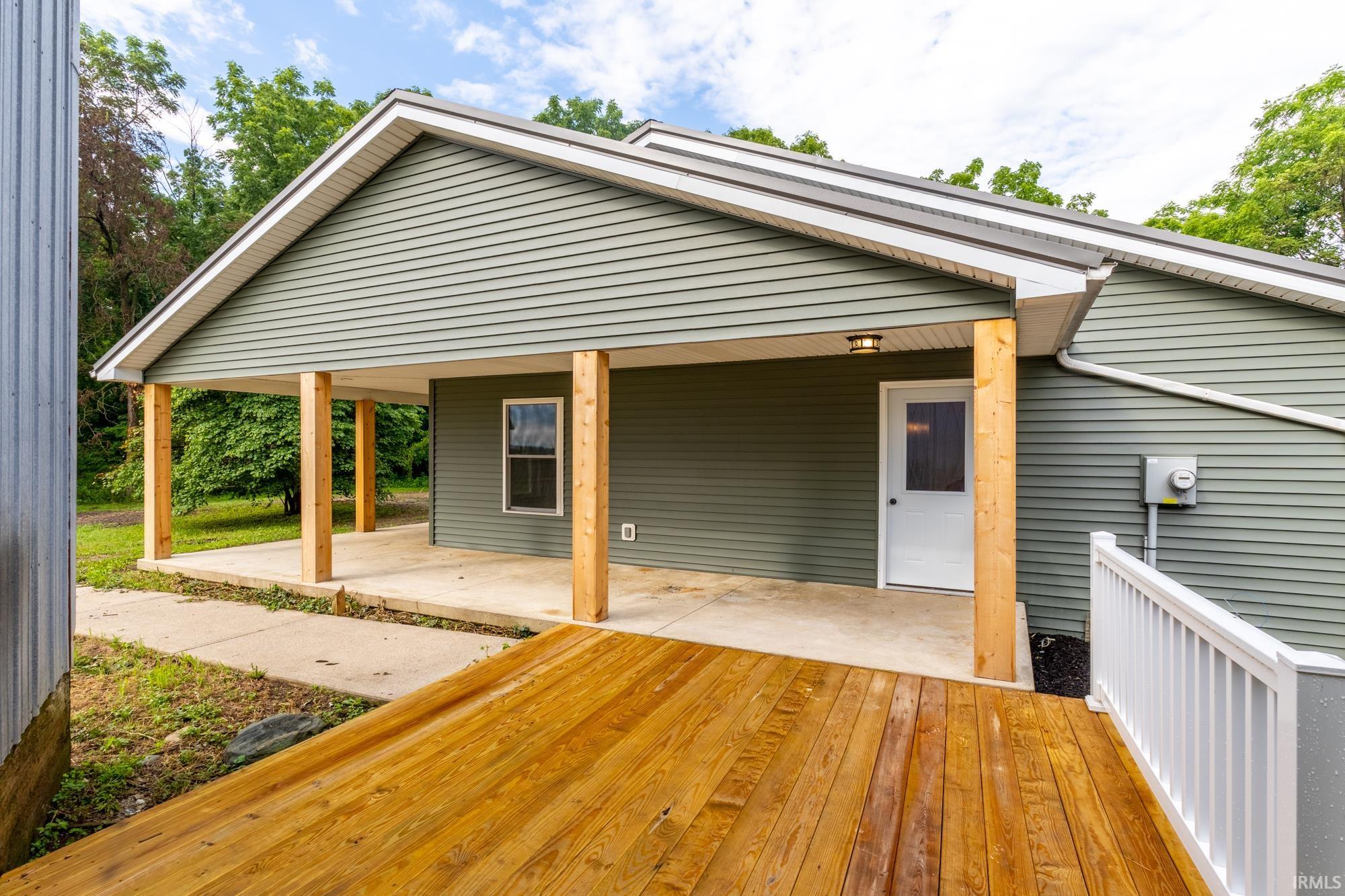 Covered front entrance with a newly constructed wood-finish deck