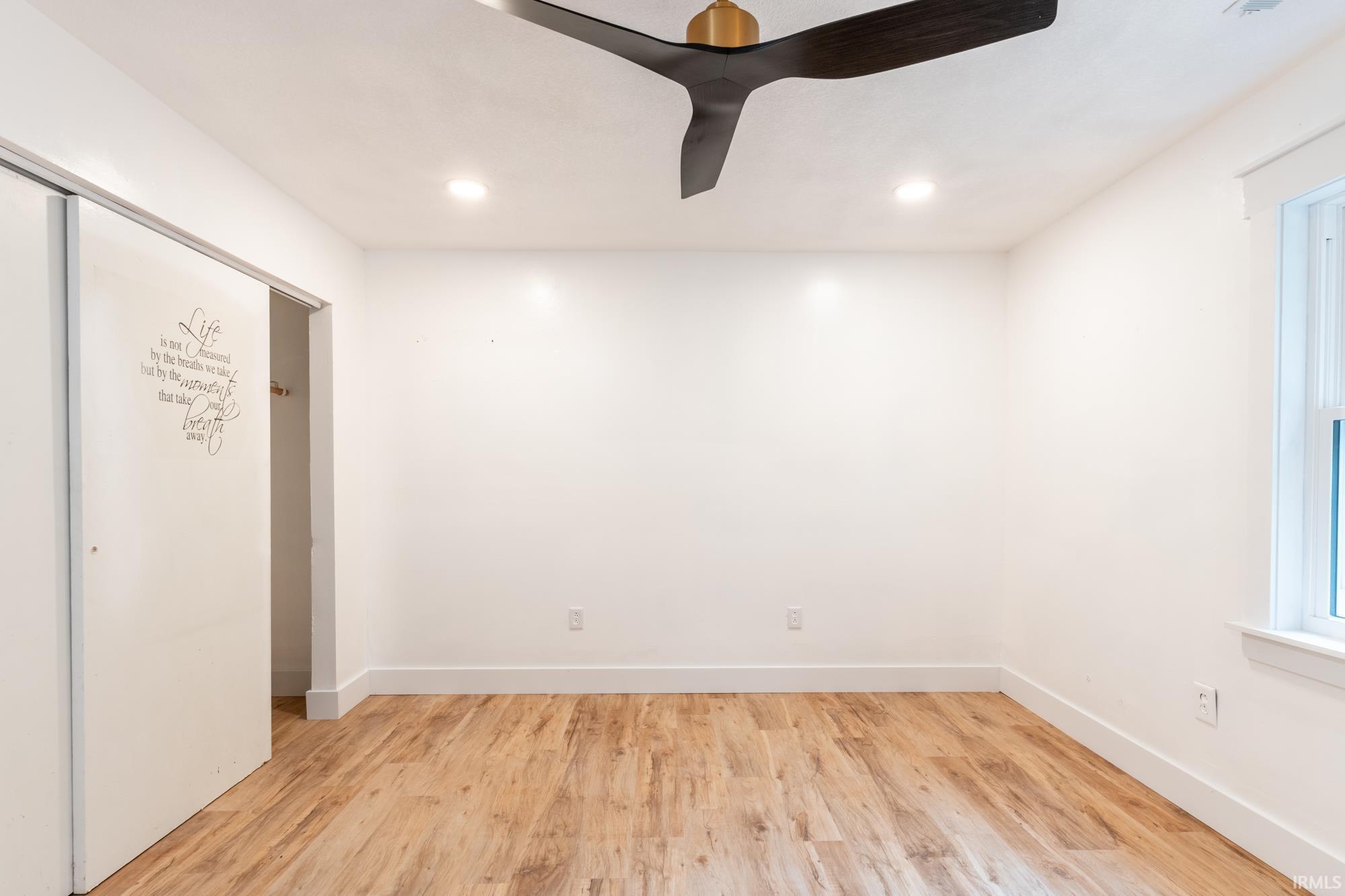 Bright room with wood-finish flooring and a contemporary ceiling fan