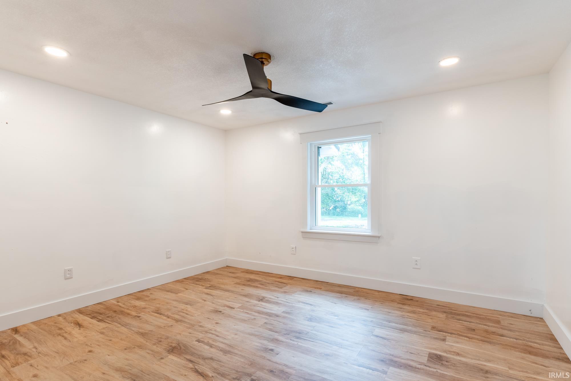 Room featuring wood-finish flooring, white walls, and recessed lighting