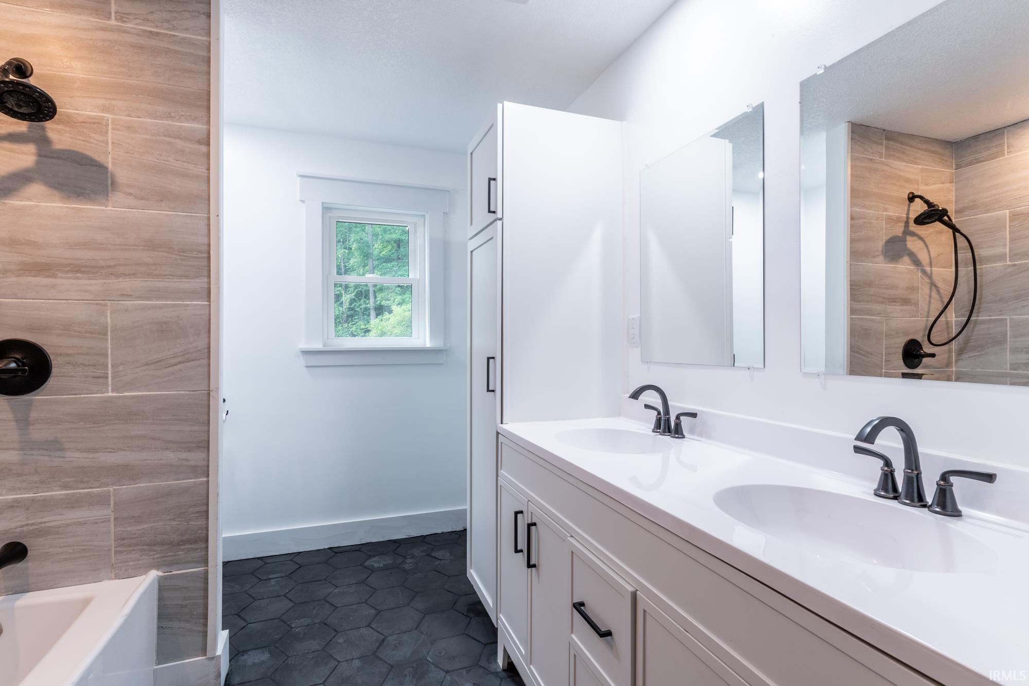 Double vanity with integrated sinks, matte black fixtures, and framed mirrors