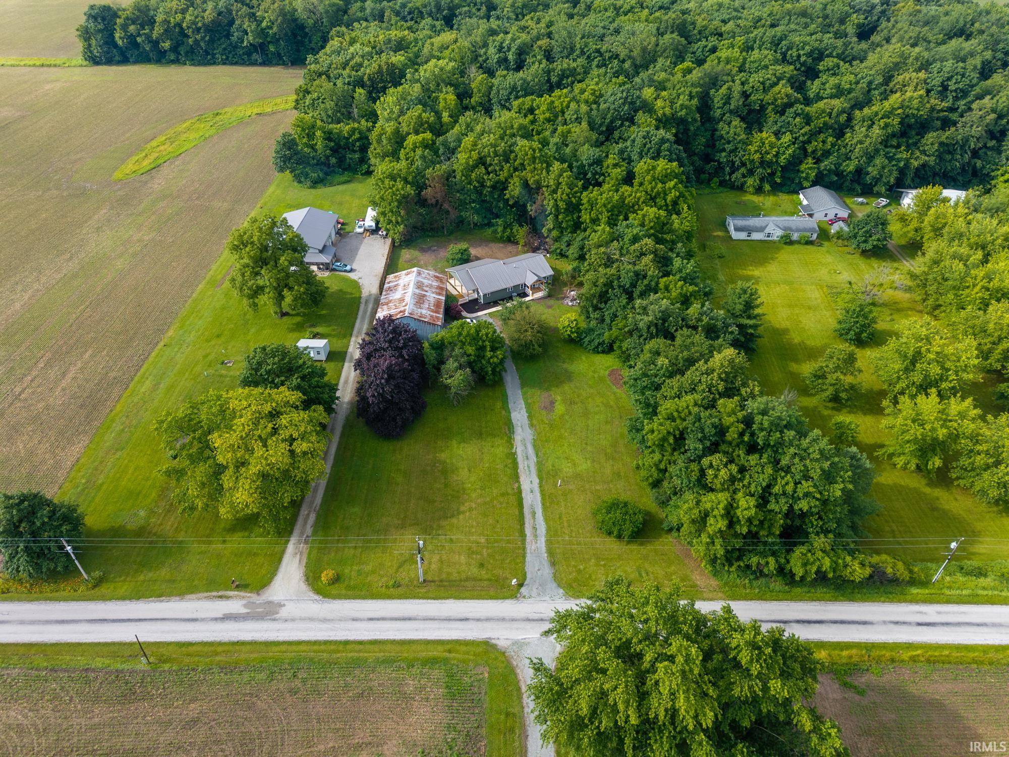 Expansive property featuring mature trees, multiple outbuildings, and two residential structures