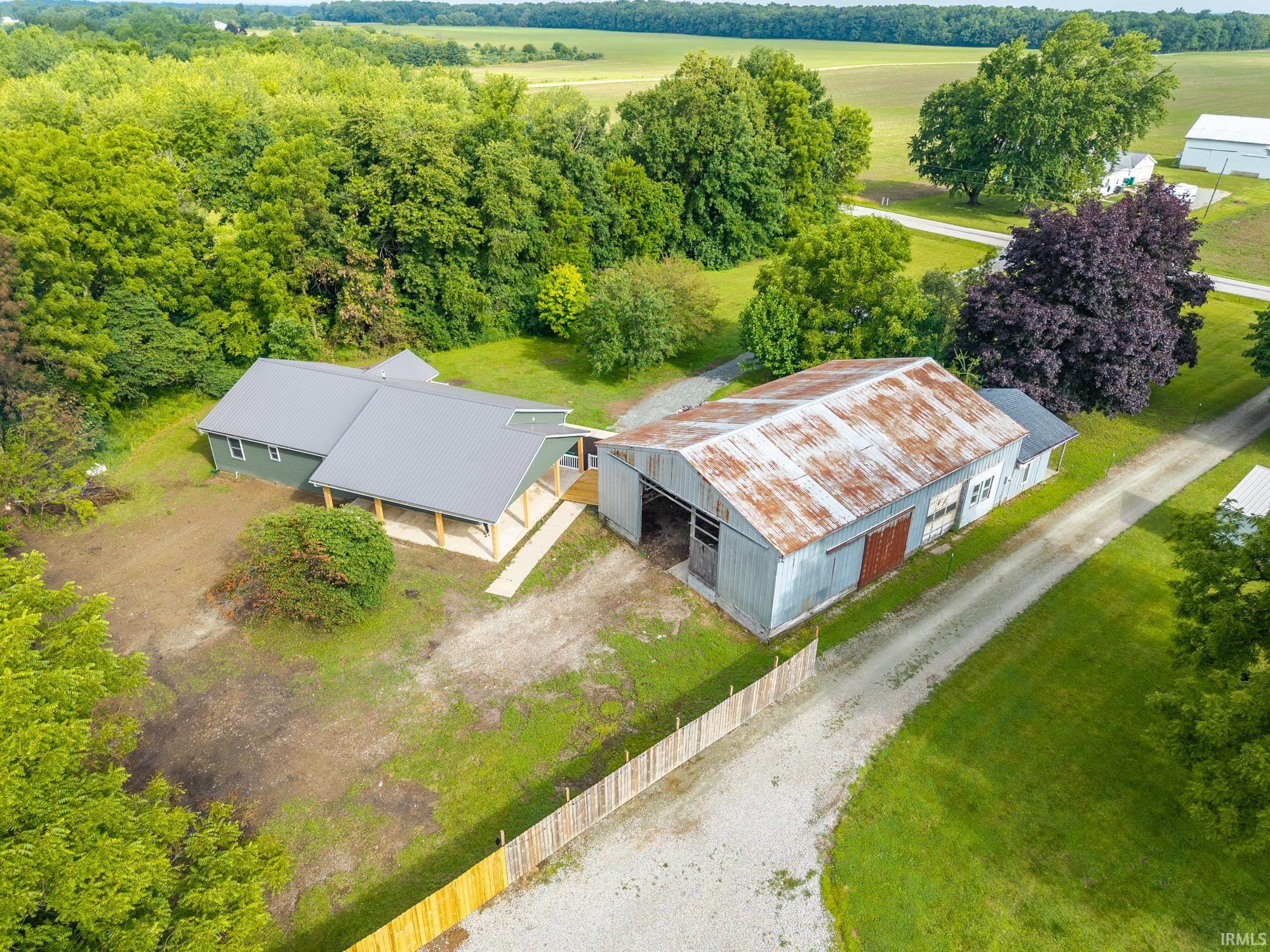 Property featuring a contemporary green exterior with a gray metal roof, covered porch, and a gravel driveway