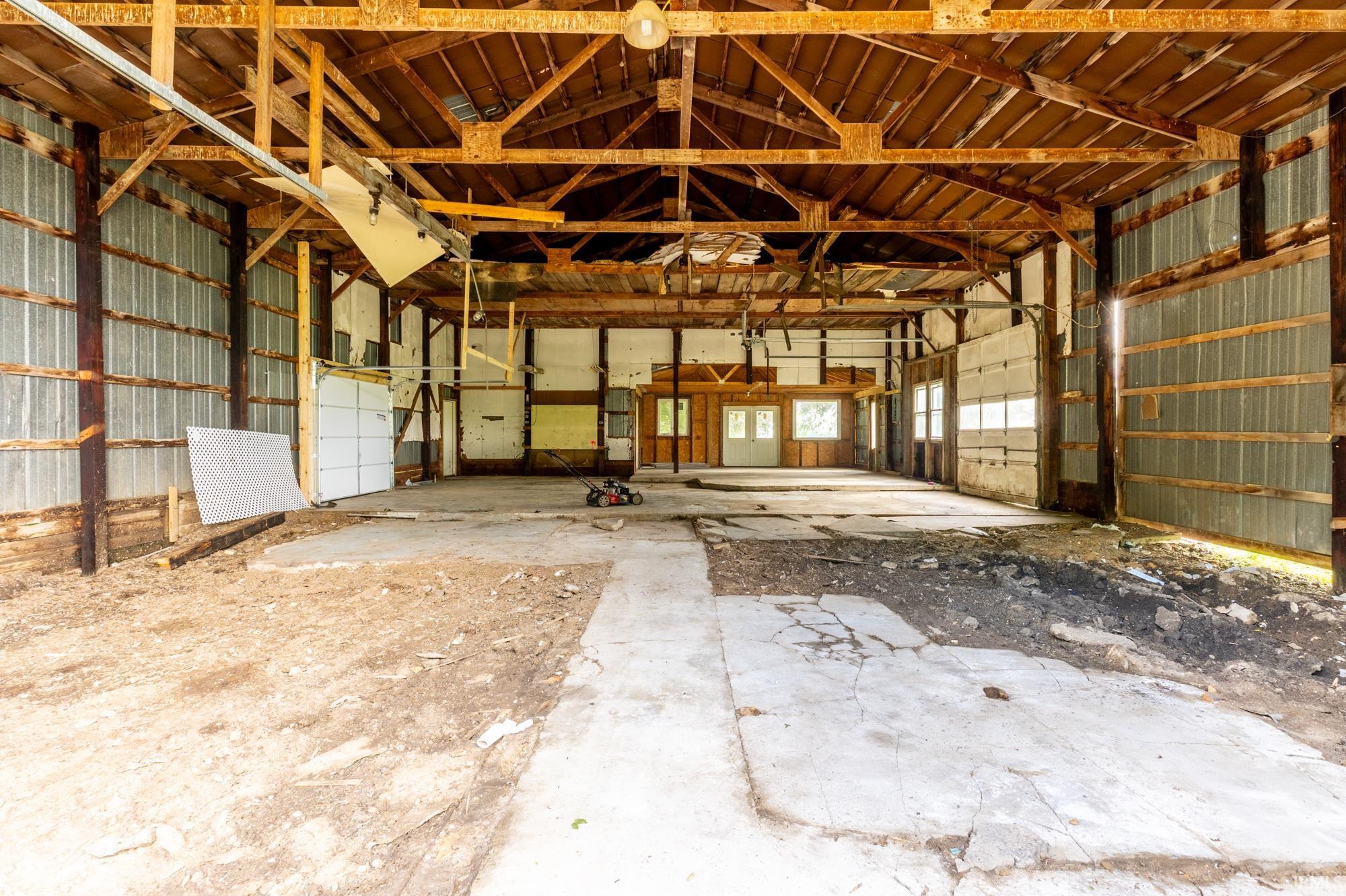 Spacious interior with exposed wood beam ceiling, concrete flooring, and corrugated metal wall panels
