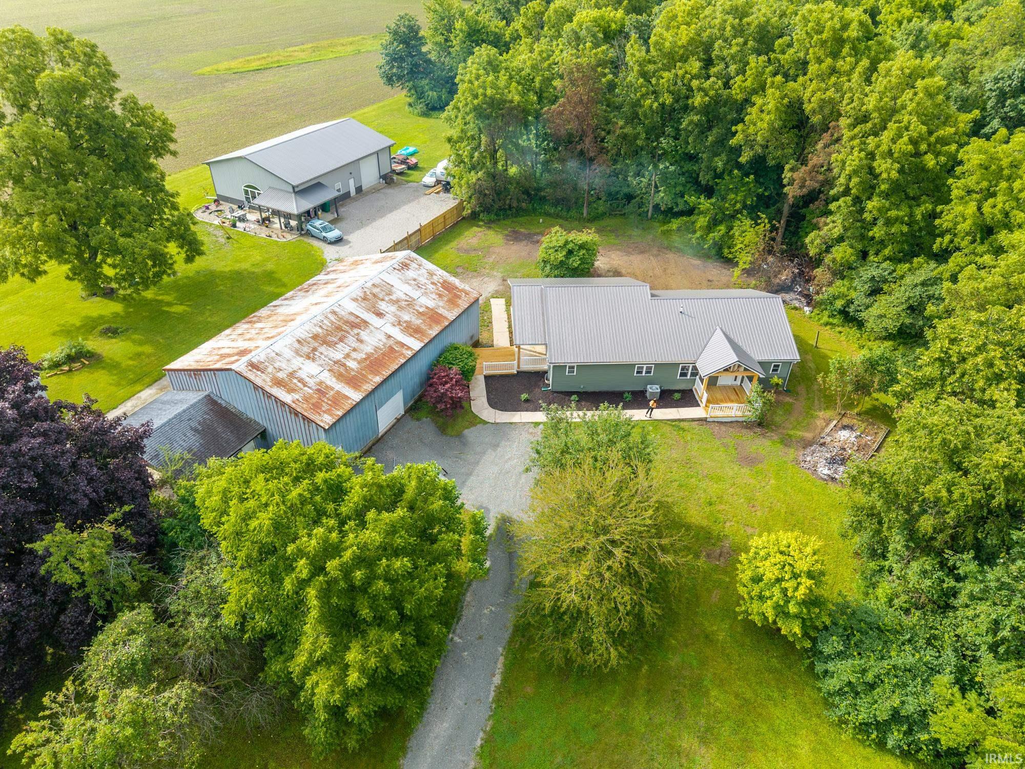 Expansive property featuring a residence with a covered front porch, a large detached garage, and an additional outbuilding