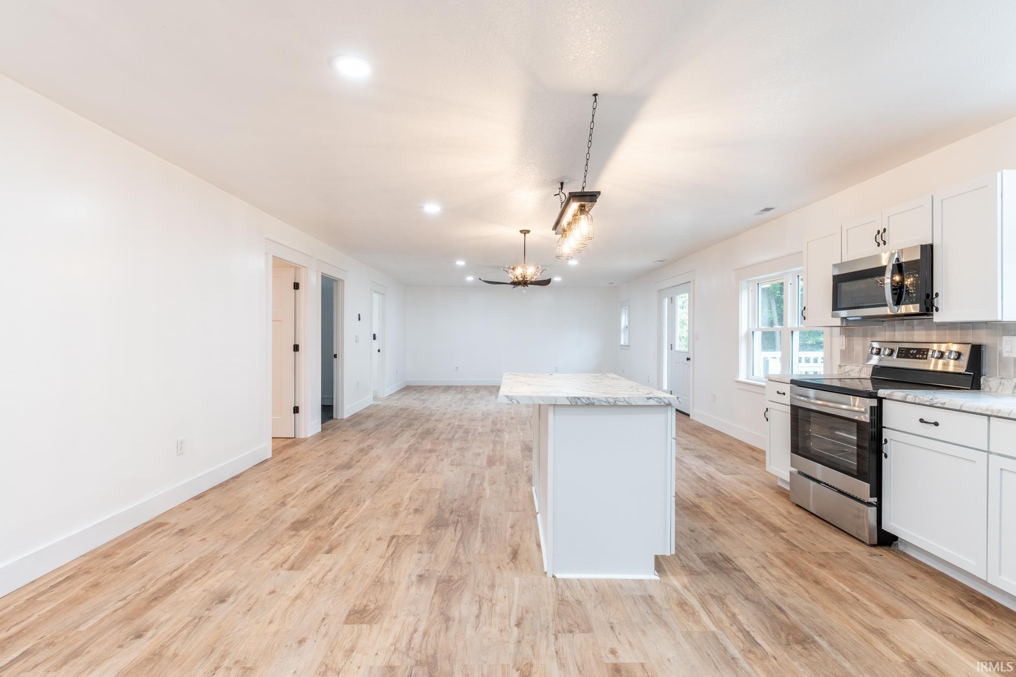 Open-concept living space featuring wood-finish flooring, recessed lighting, and a kitchen island with a stone countertop