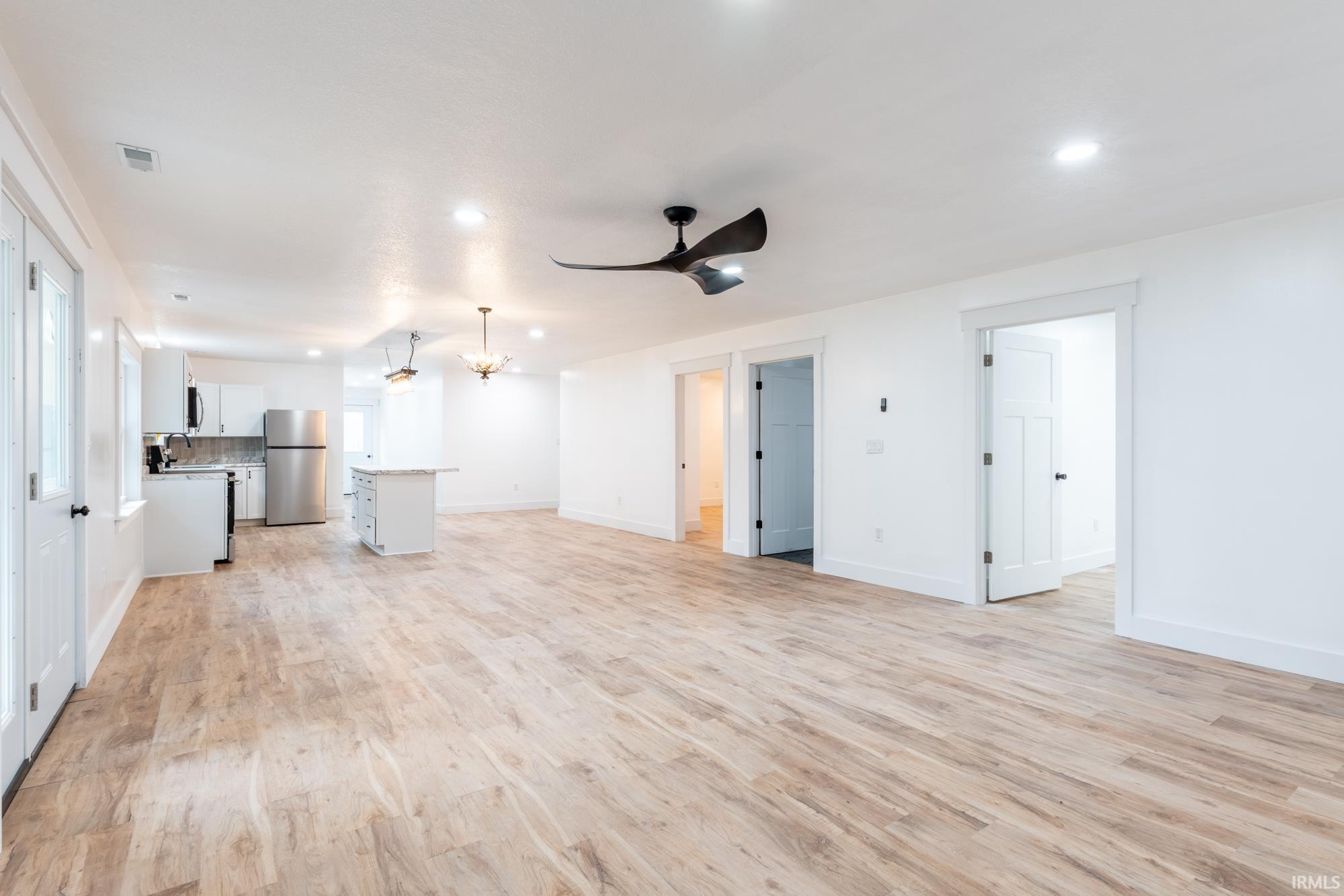 Expansive open-concept space featuring wood-finish flooring, recessed lighting, and a modern ceiling fan