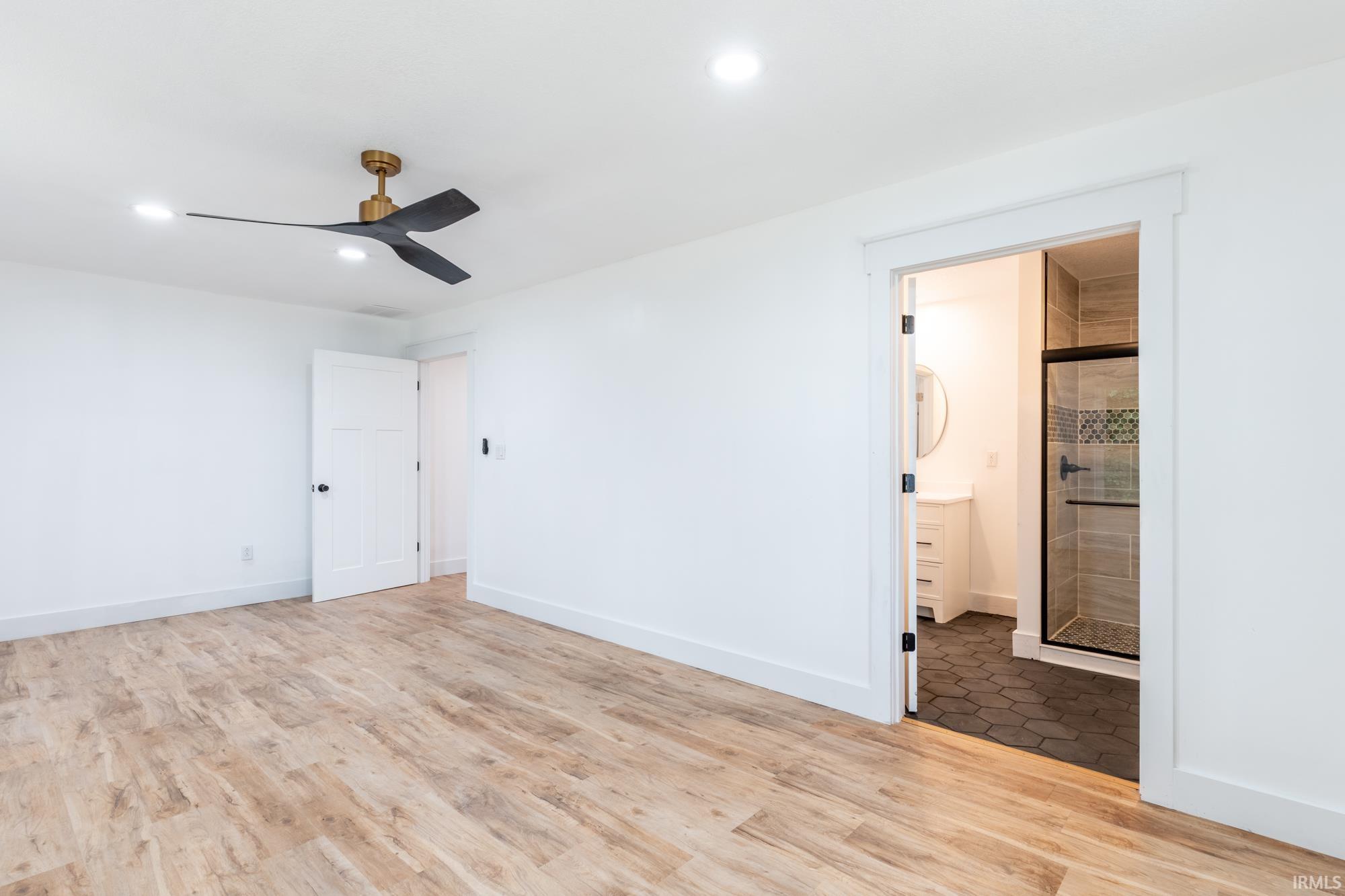 Bright interior with wood-finish flooring, a contemporary ceiling fan, and recessed lighting