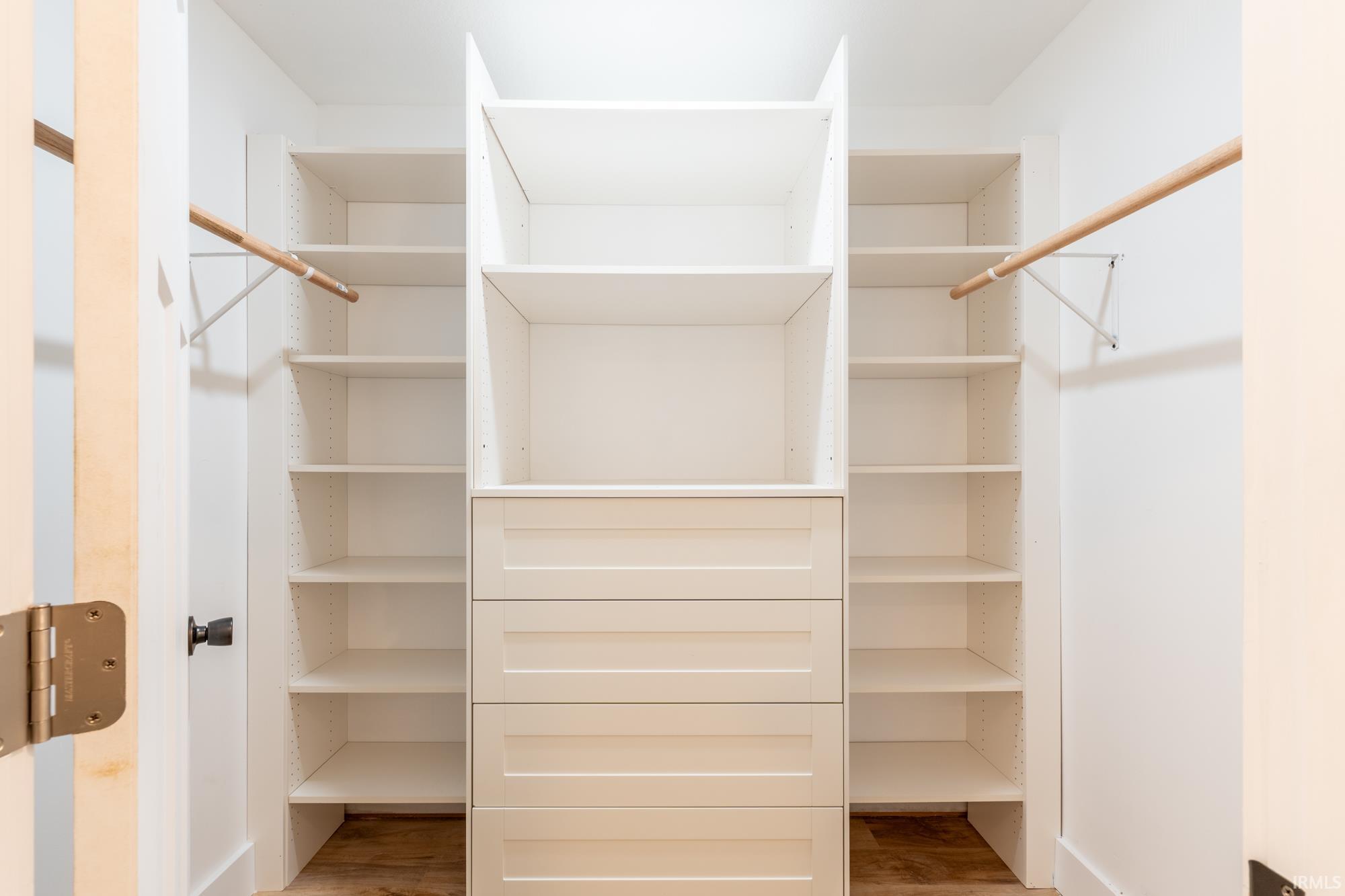 Custom white built-in closet system featuring multiple shelves, hanging rods, and integrated drawers