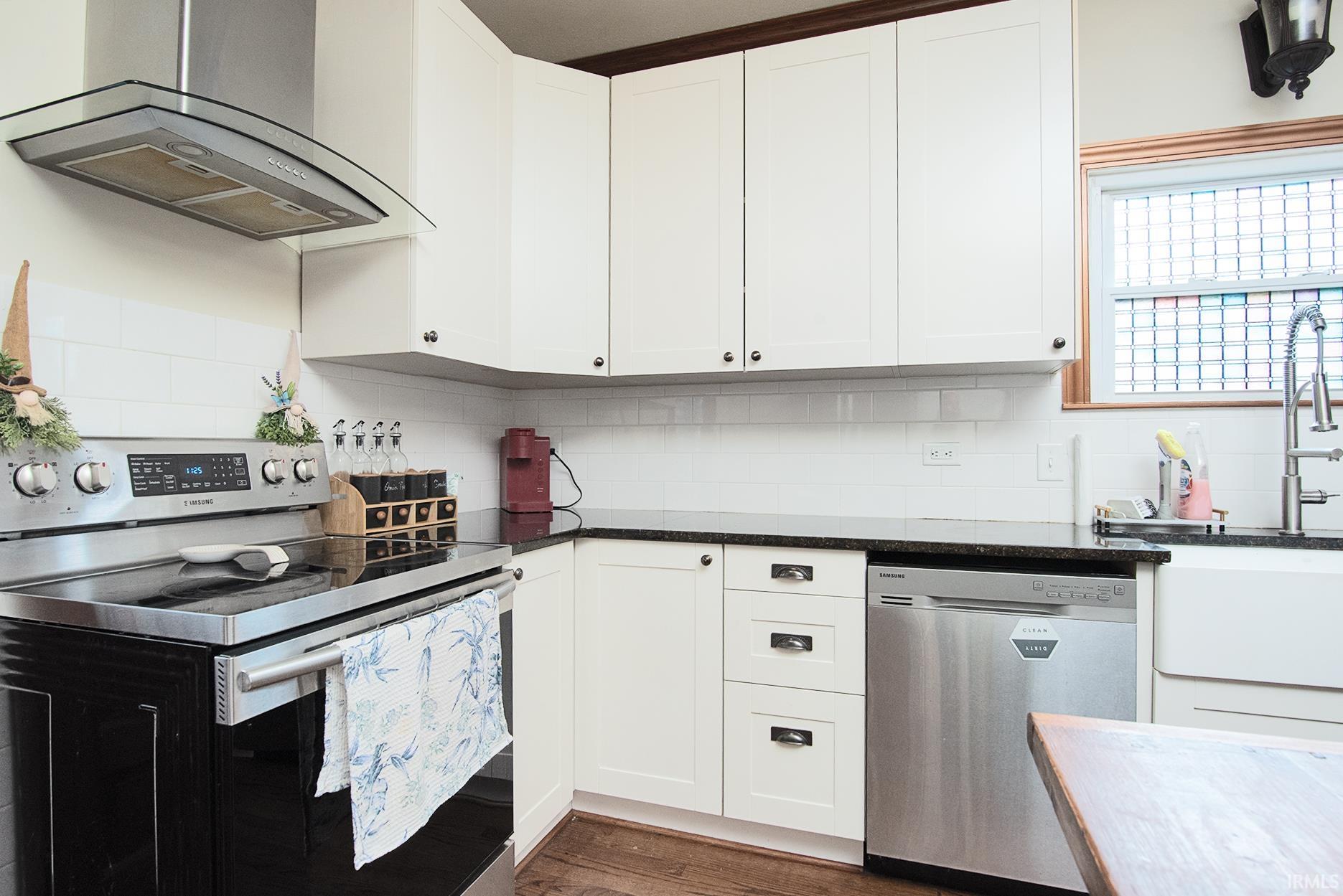 Kitchen featuring white shaker cabinetry, dark countertops, and a white subway tile backsplash