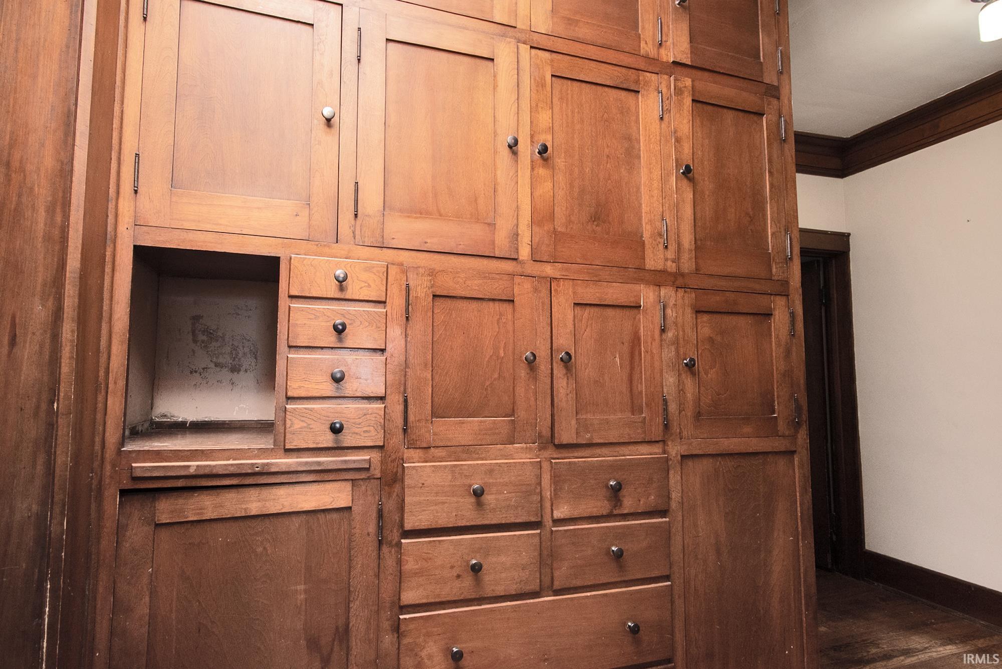 Extensive built-in wood cabinetry with various cabinet doors and multiple drawers, featuring dark hardware