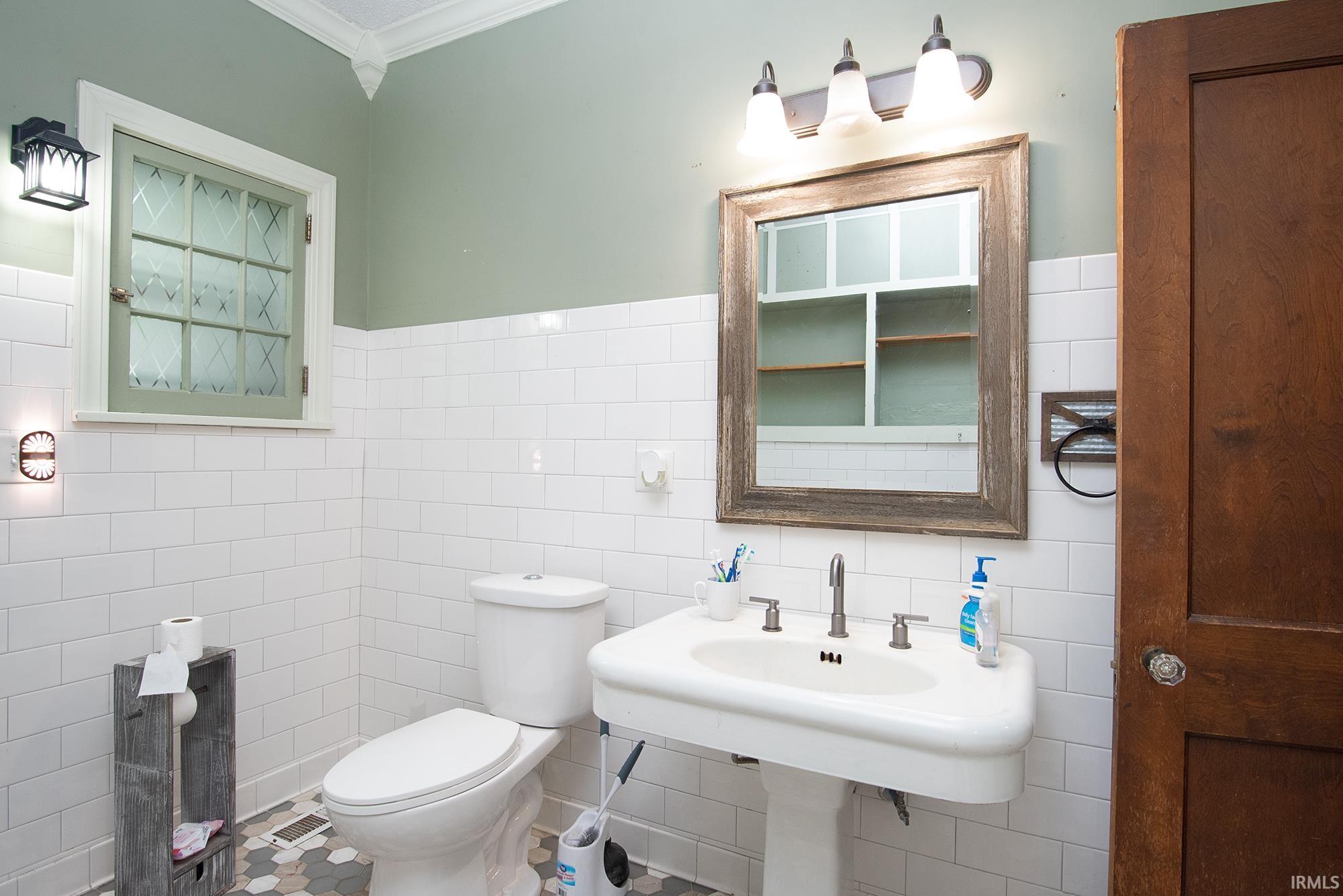 Bathroom featuring a pedestal sink, white subway tile walls, and hexagonal floor tiles