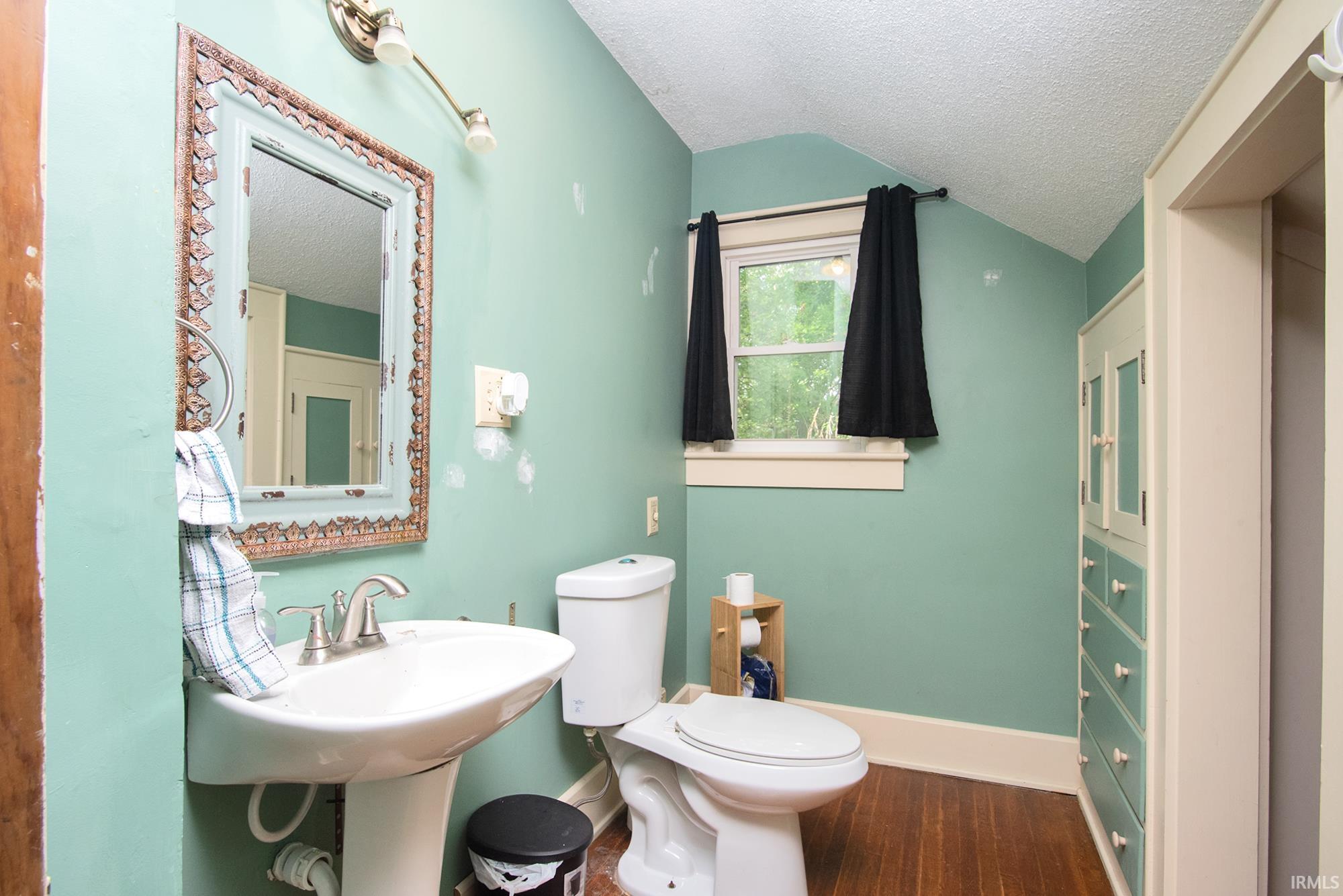 Pedestal sink with brushed nickel faucet, framed wall mirror, and built-in storage cabinetry