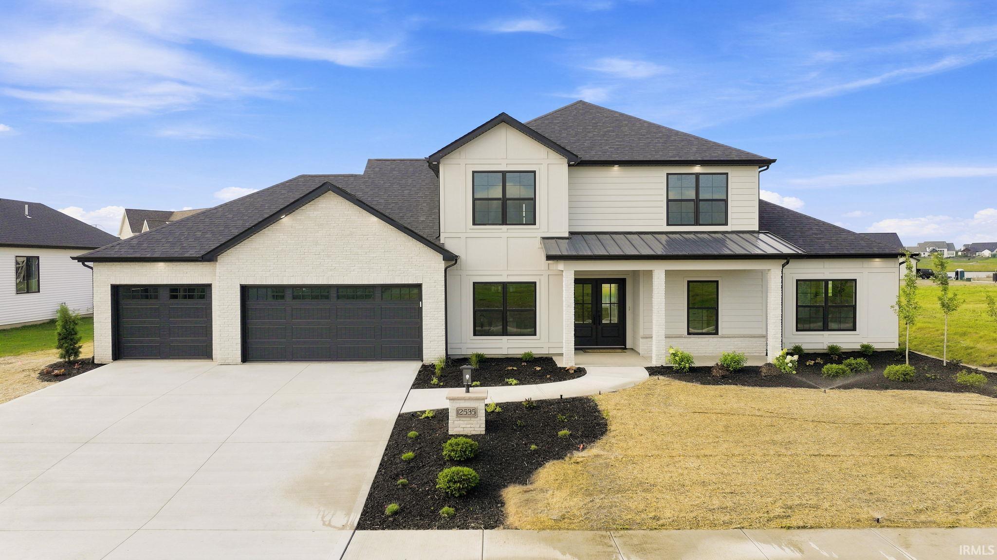 Modern farmhouse-style residence featuring a white brick and siding exterior with black framed windows