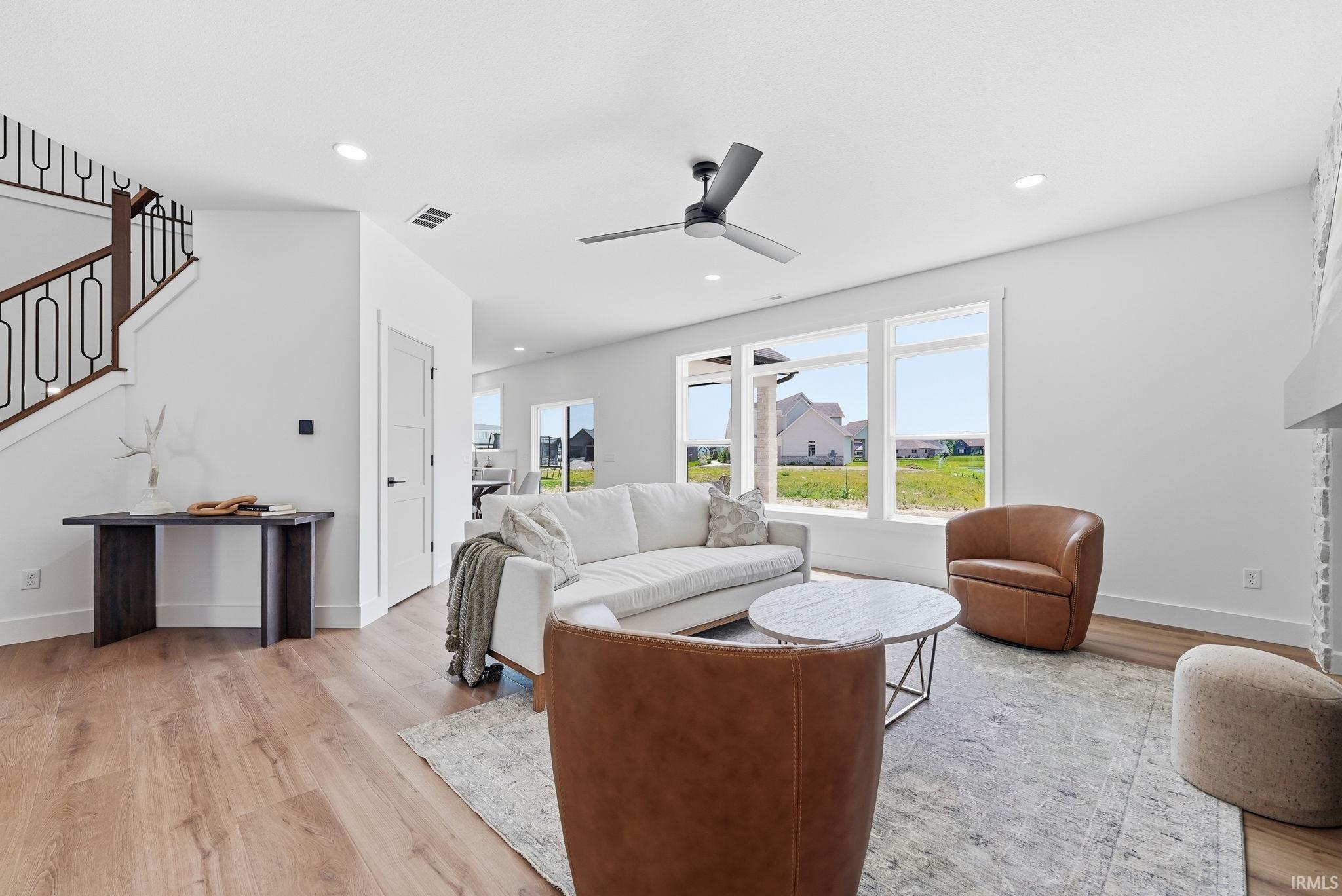 Spacious living area featuring light wood-finish flooring, recessed lighting, and a modern ceiling fan
