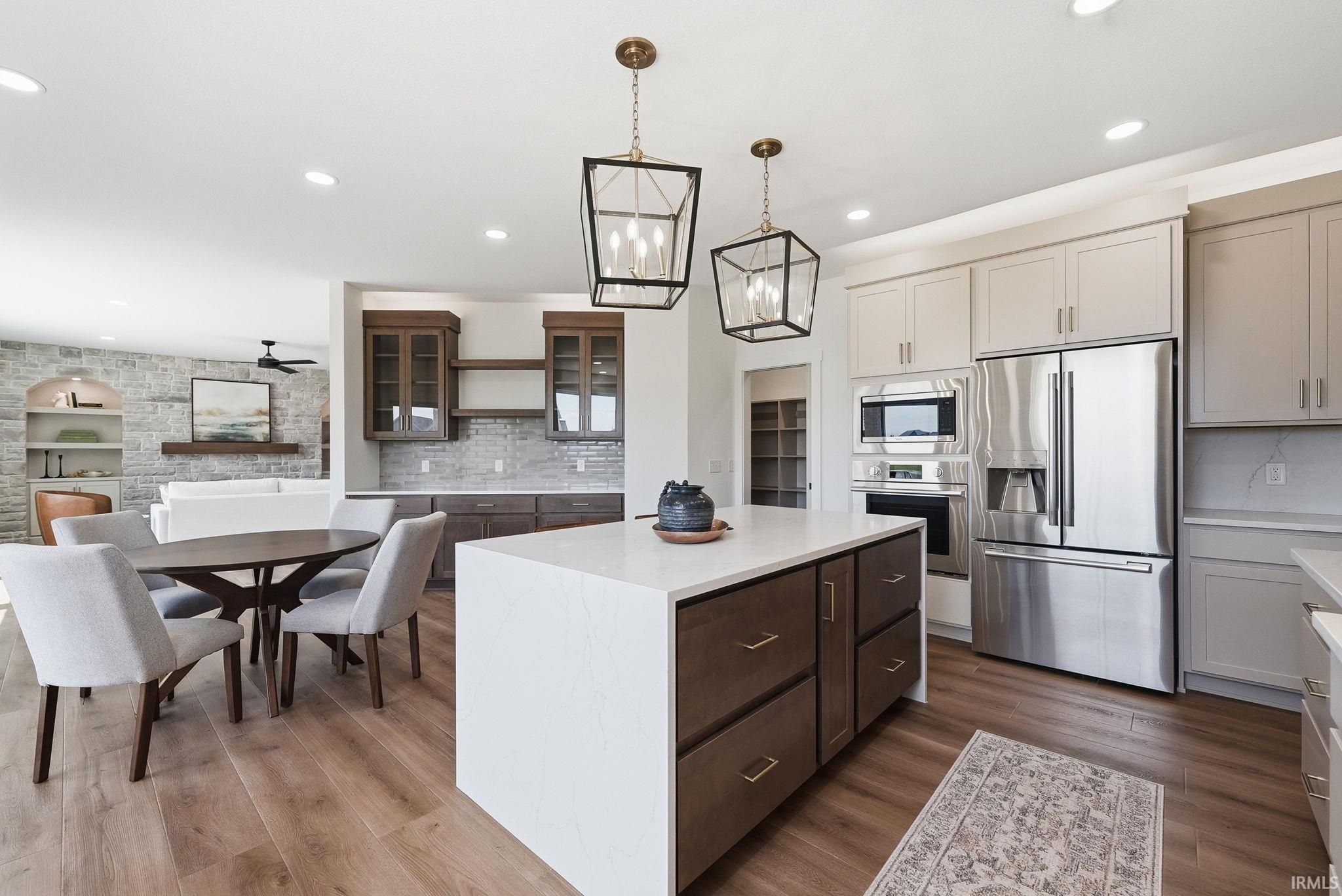 Modern kitchen featuring a large central island with a solid surface countertop, stainless steel appliances, and recessed lighting