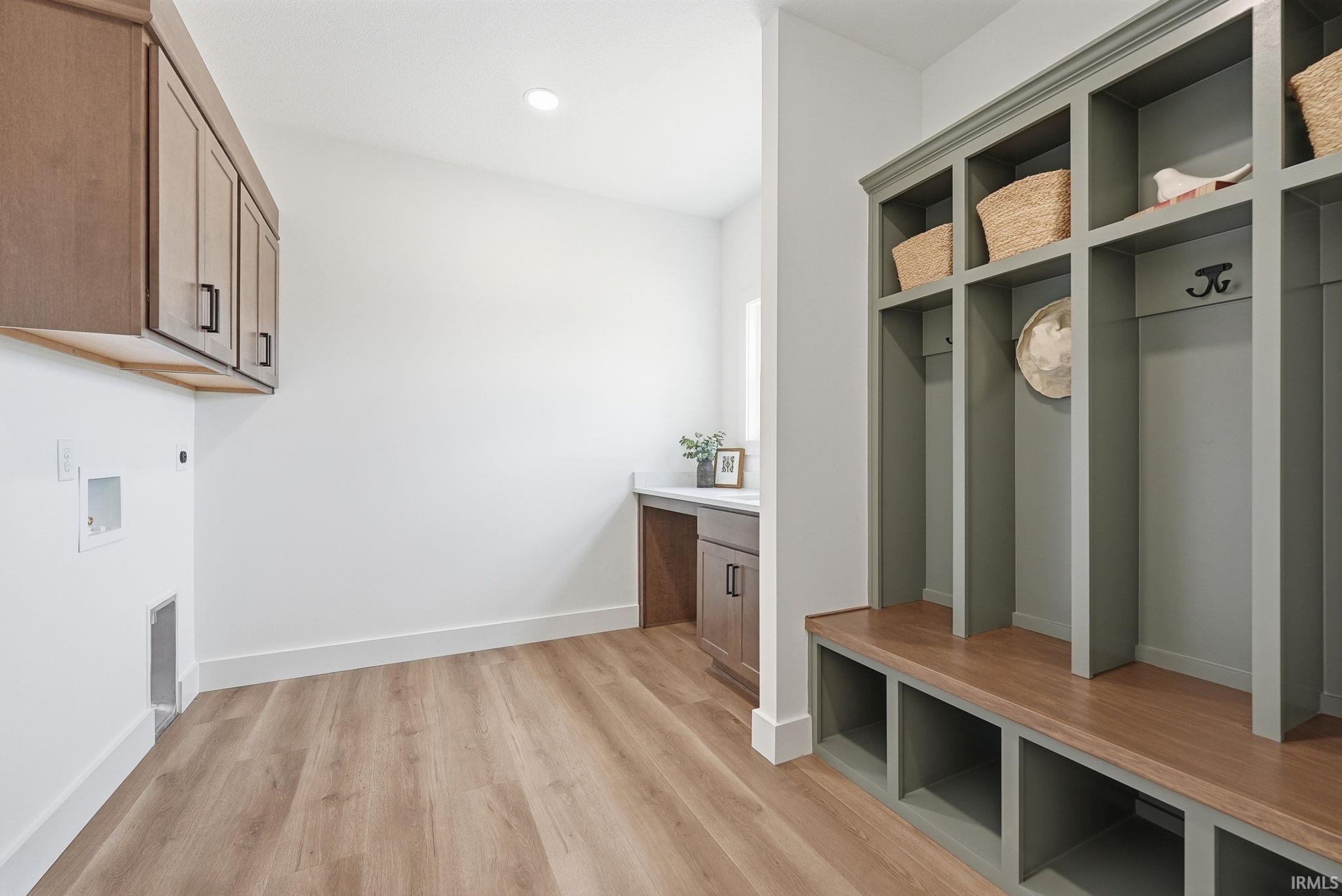 Mudroom/laundry area featuring wood-finish flooring, white walls, and built-in cabinetry