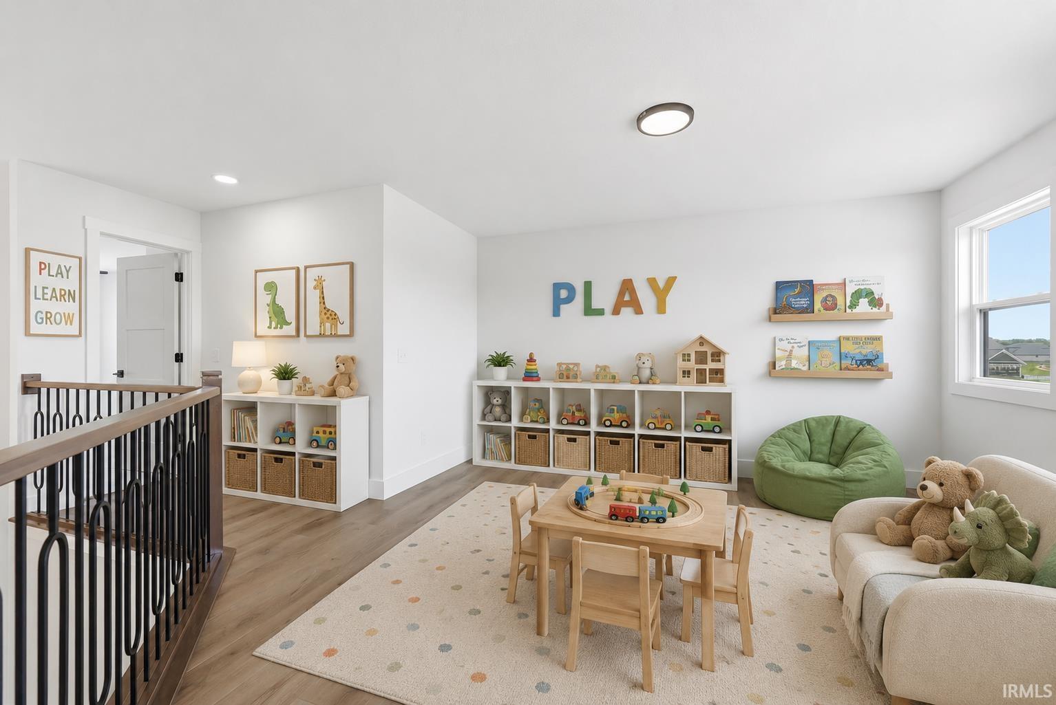 Bright loft area featuring wood-finish flooring and white walls