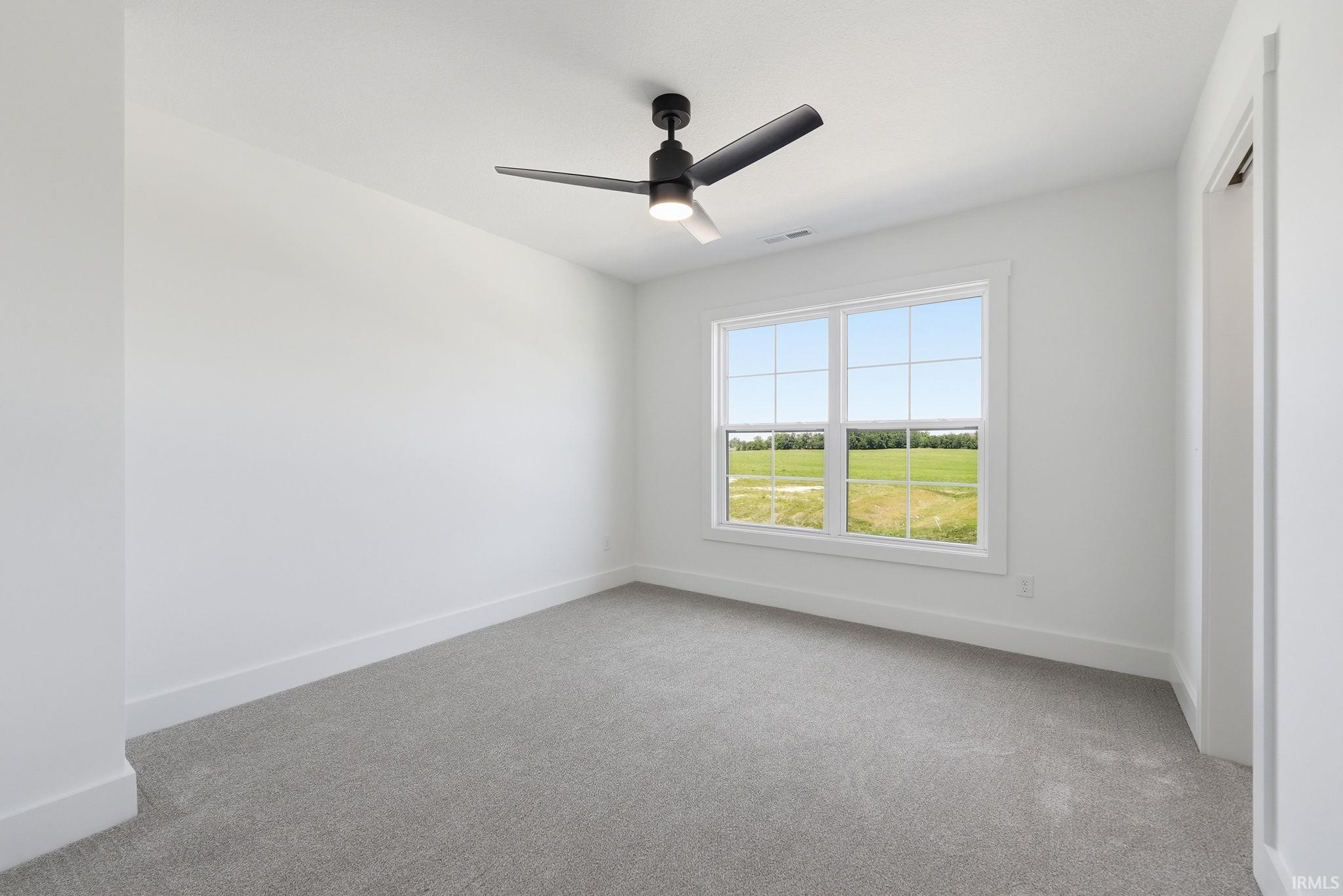 Room featuring a large window with gridded panes, ceiling fan with integrated lighting, broad baseboards, and neutral-toned carpeting