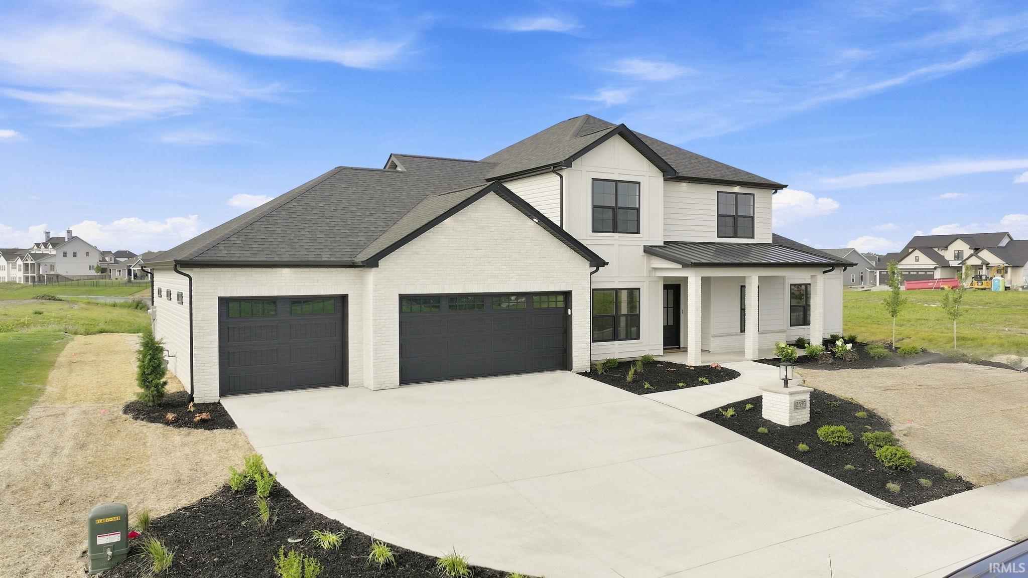 Modern two-story residence featuring a white brick and siding exterior with dark trim