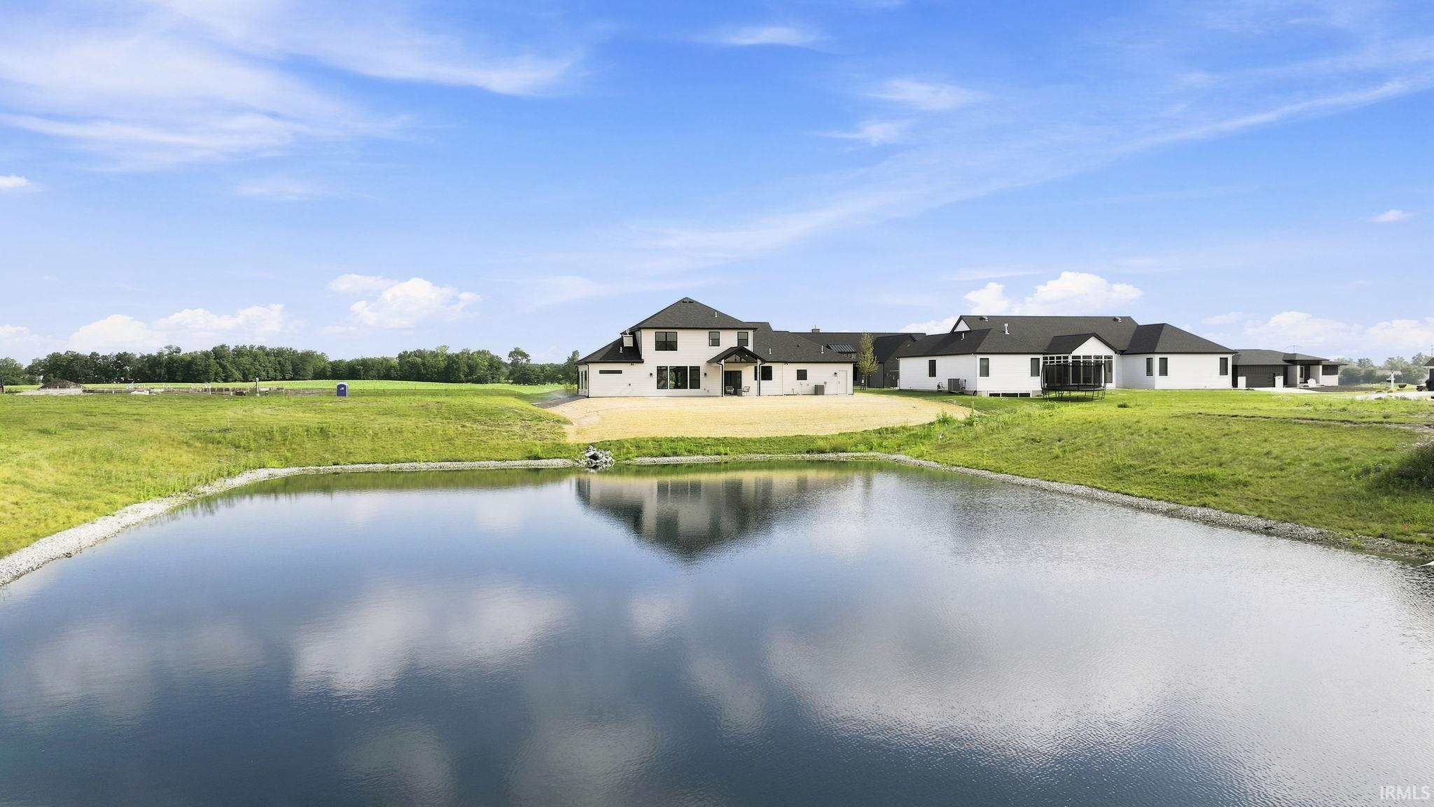 Expansive waterfront property featuring a large pond reflecting the blue sky