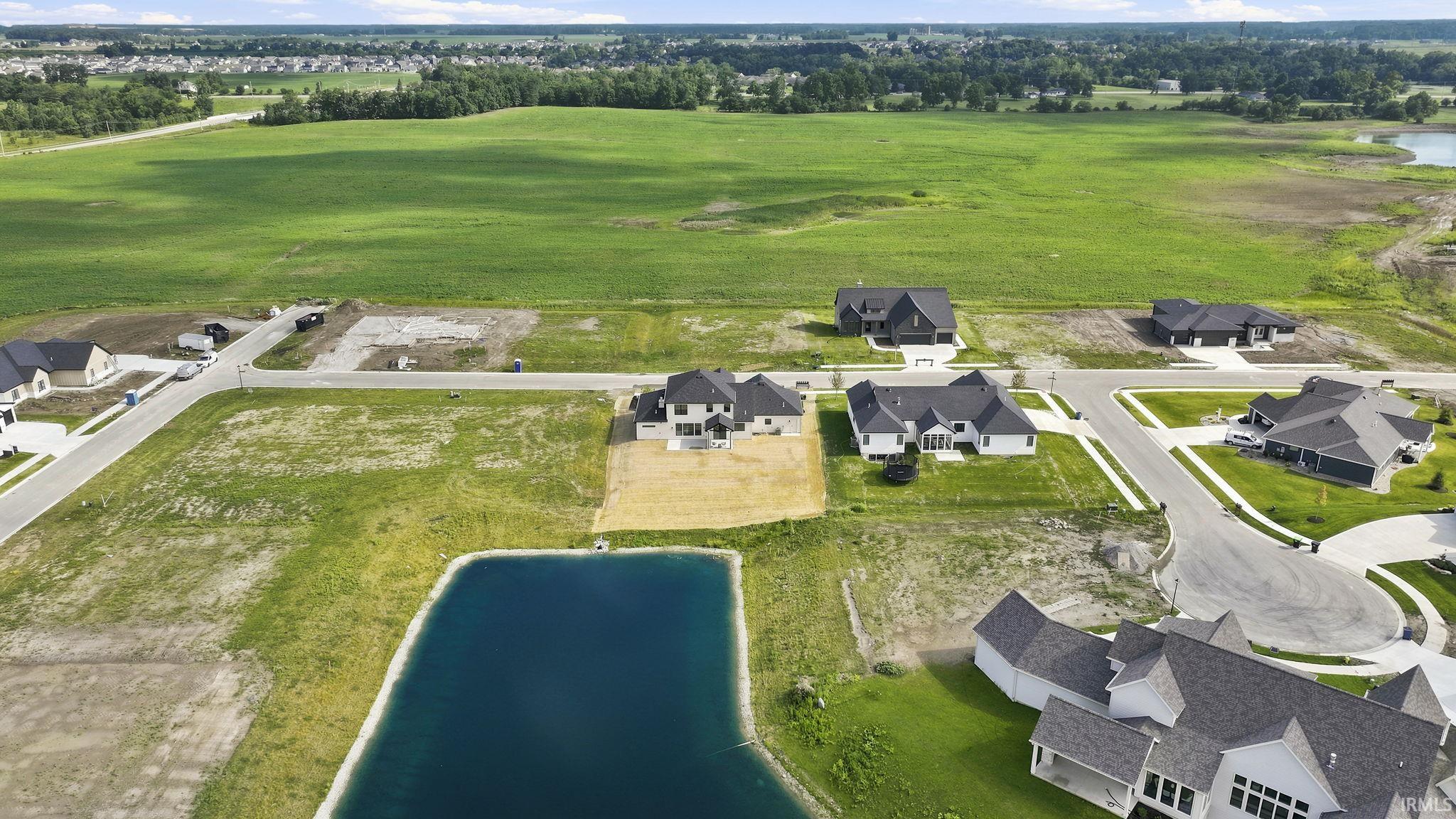 Aerial perspective of a developing residential community, featuring a tranquil pond