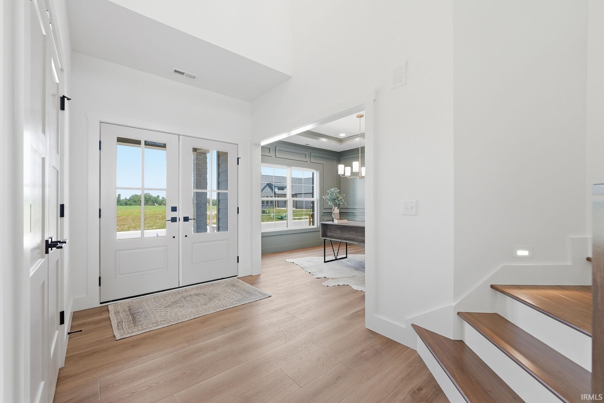 Double entry doors with divided lites and matte black hardware, showcasing wood-finish flooring throughout